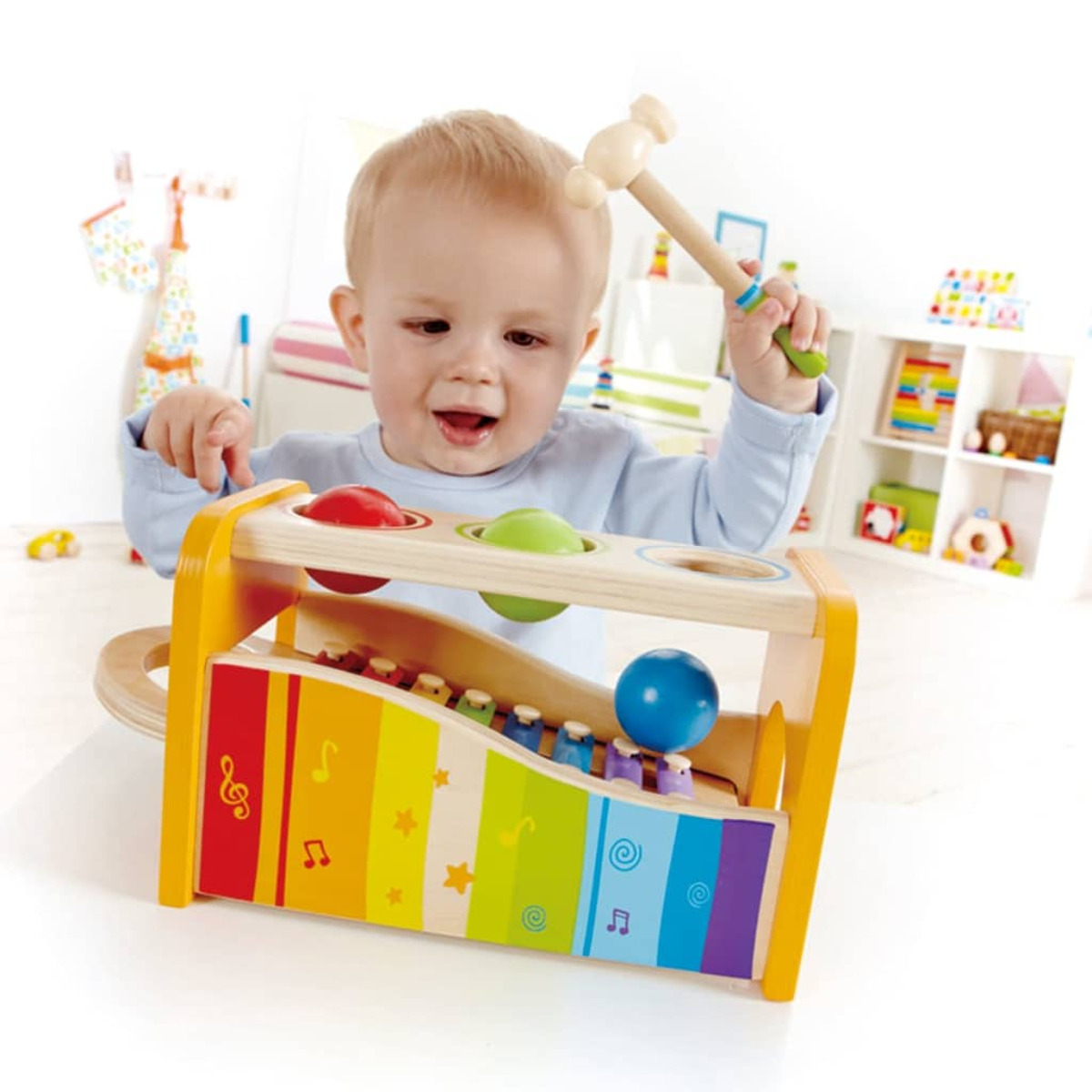 Kind spielt mit einem Spielzeug-Xylophon. Holzspielzeug mit Regenbogen-Tasten und orangefarbenem Rahmen.
