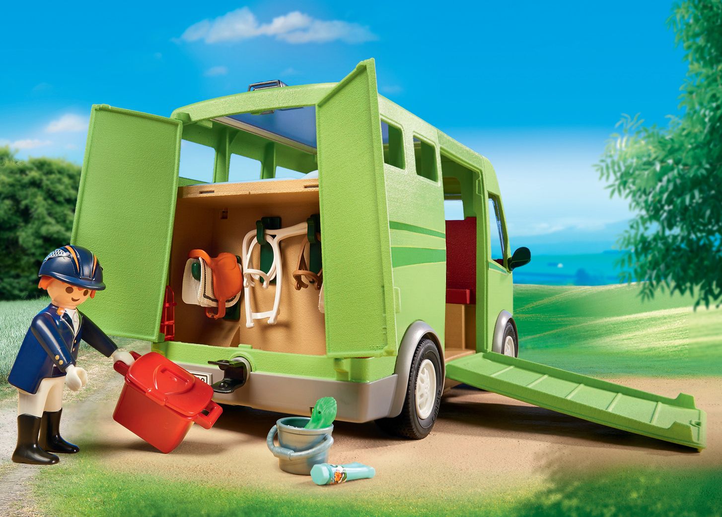 Zabawkowa przyczepa dla koni z figurką. Przyczepa jest zielona, z otwartymi drzwiami. Widoczna figurka.