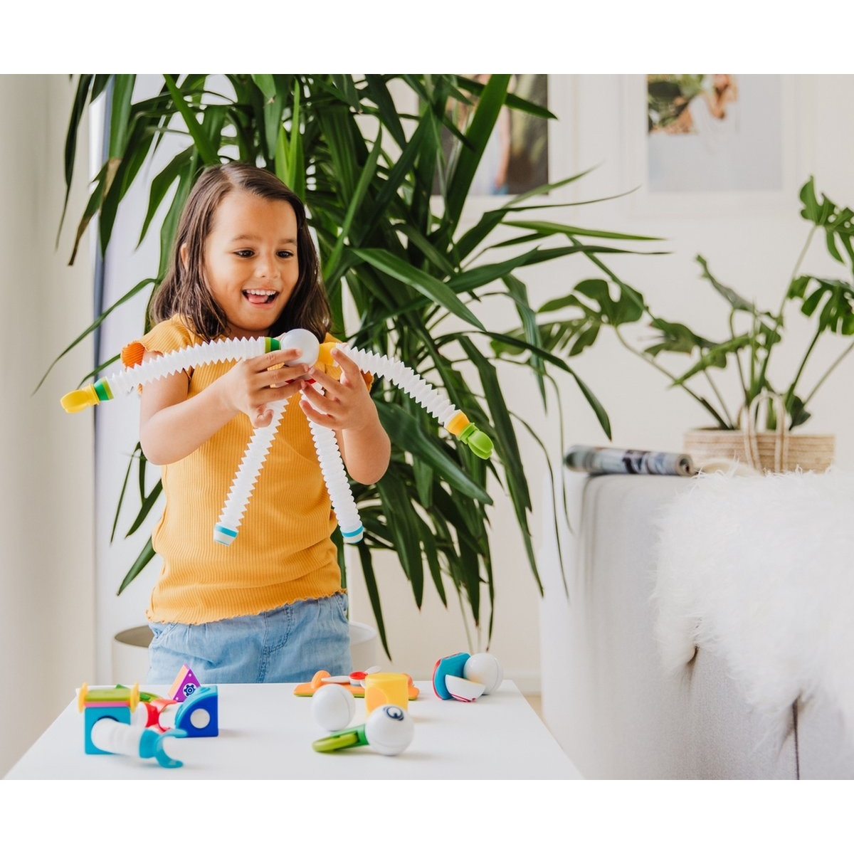 Una bambina che gioca con un giocattolo. È un gioco di costruzione con tubi bianchi.