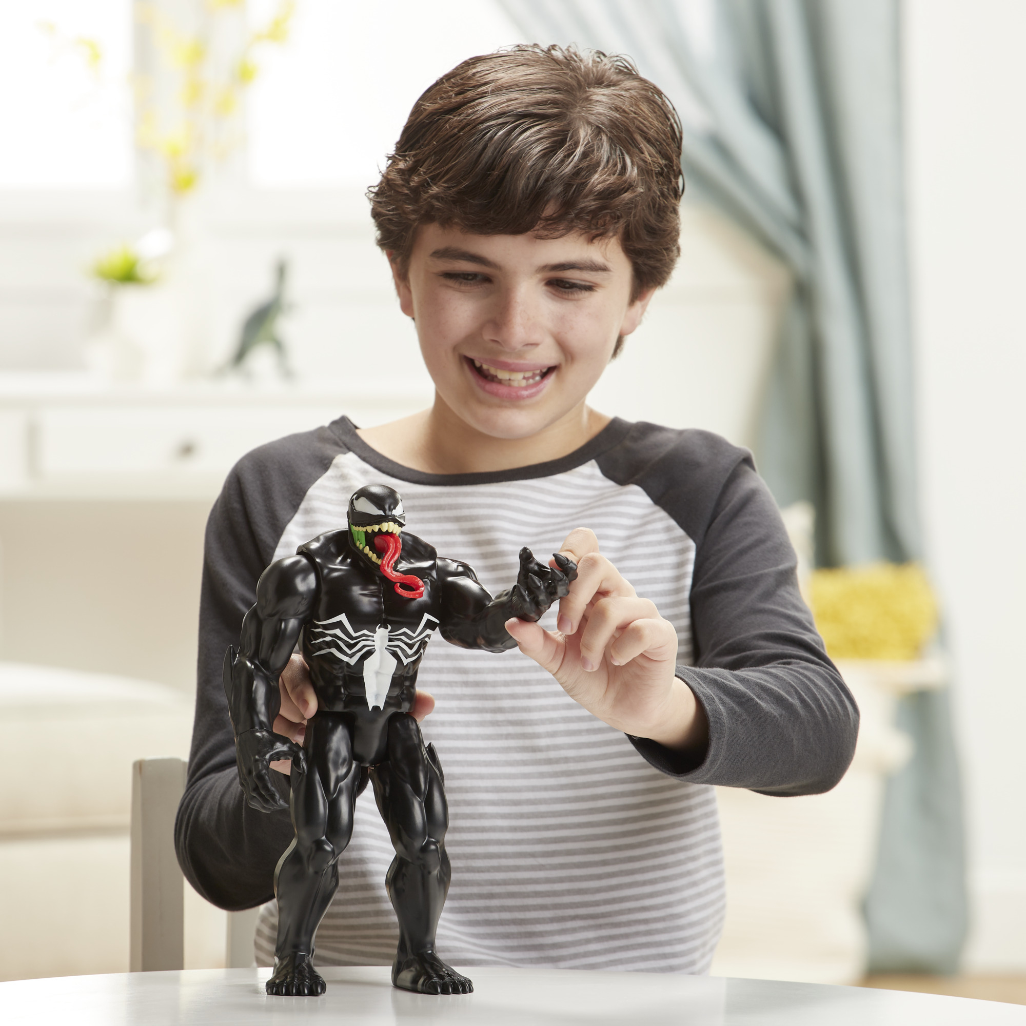 Ragazzo con giocattolo di Venom. Sorride e tiene la figura in bianco e nero.