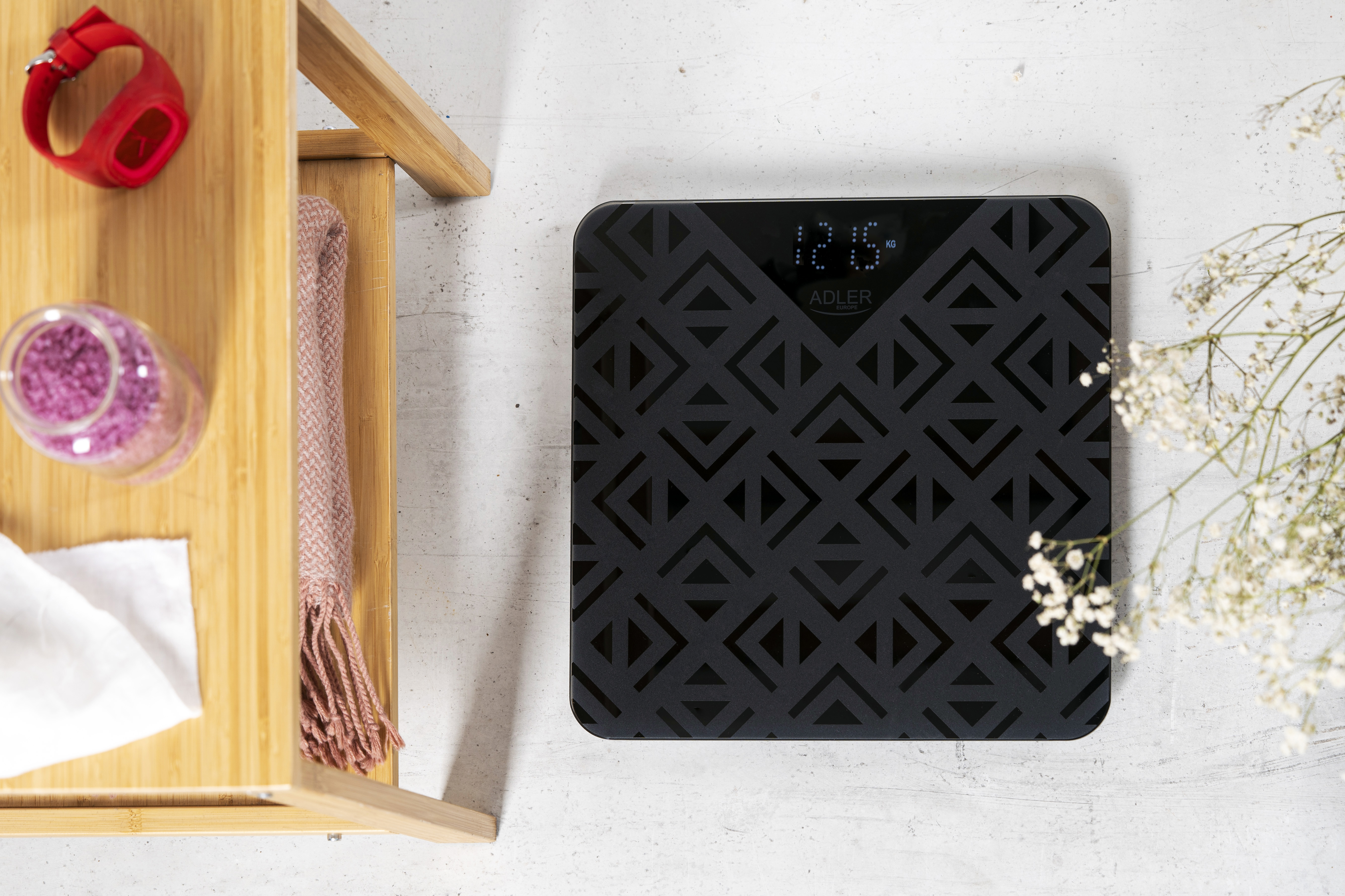 Czarna cyfrowa waga łazienkowa z geometrycznym wzorem, na białej powierzchni.