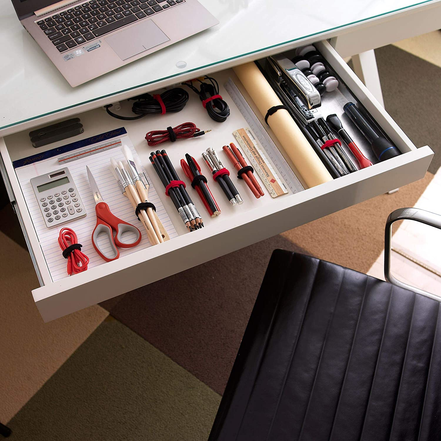 Geöffnete Schublade mit Bürobedarf: Taschenrechner, Schere, Stifte, Lineal, Tacker und Kabelbinder.