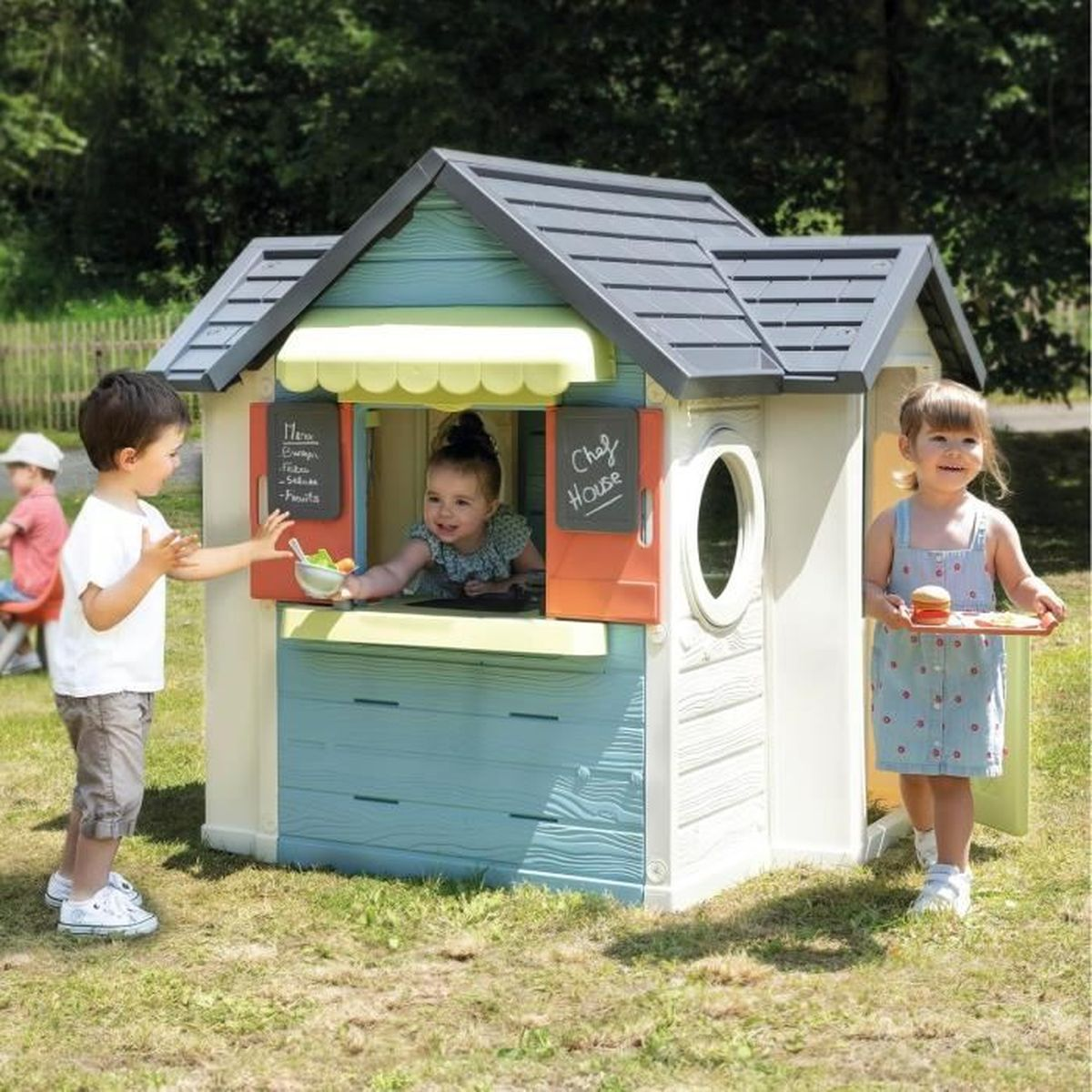 Bambini che giocano in una casa giocattolo. Uno serve cibo, due aspettano.