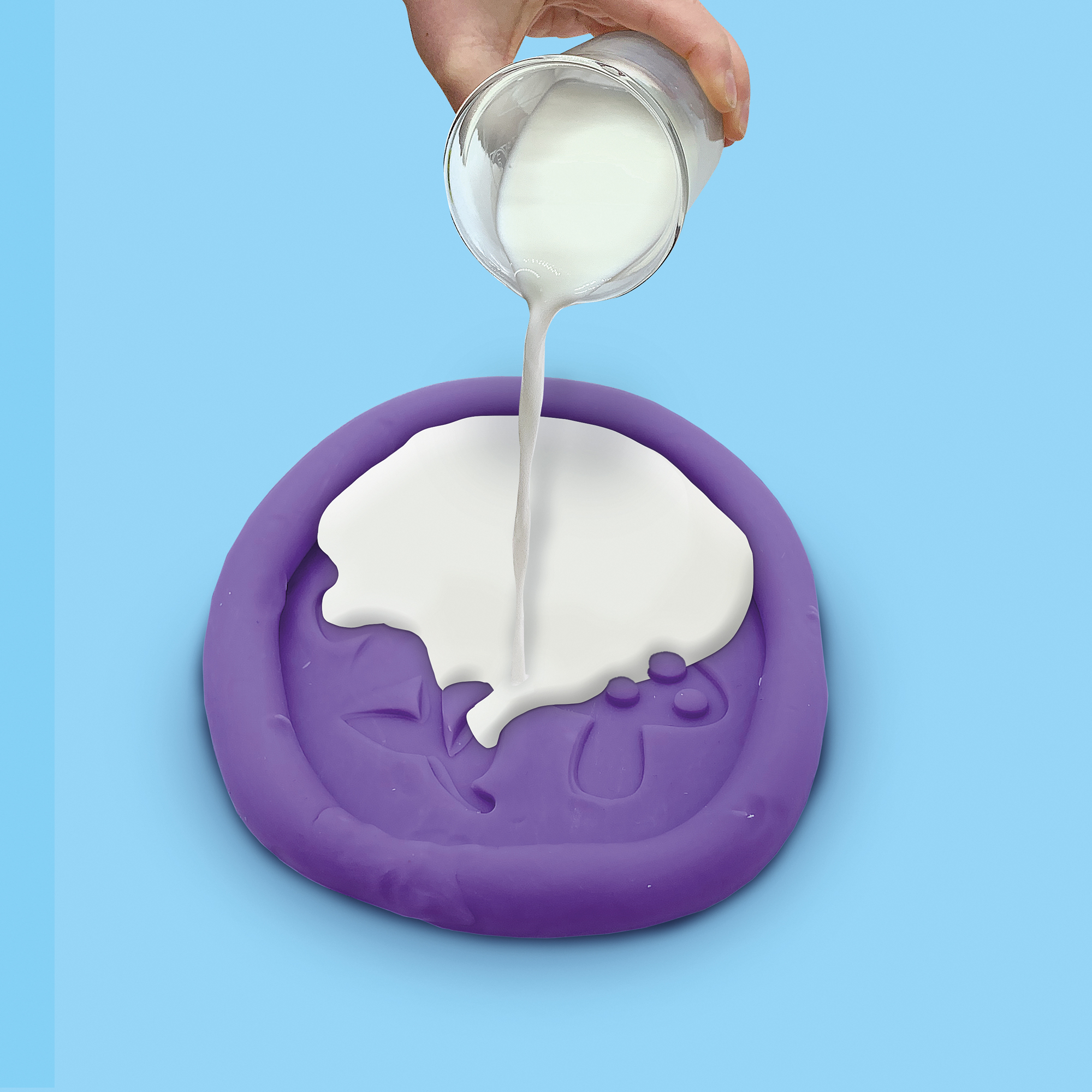 Biały płyn wylewany na fioletową tacę z kształtami kwiatów i grzybów.