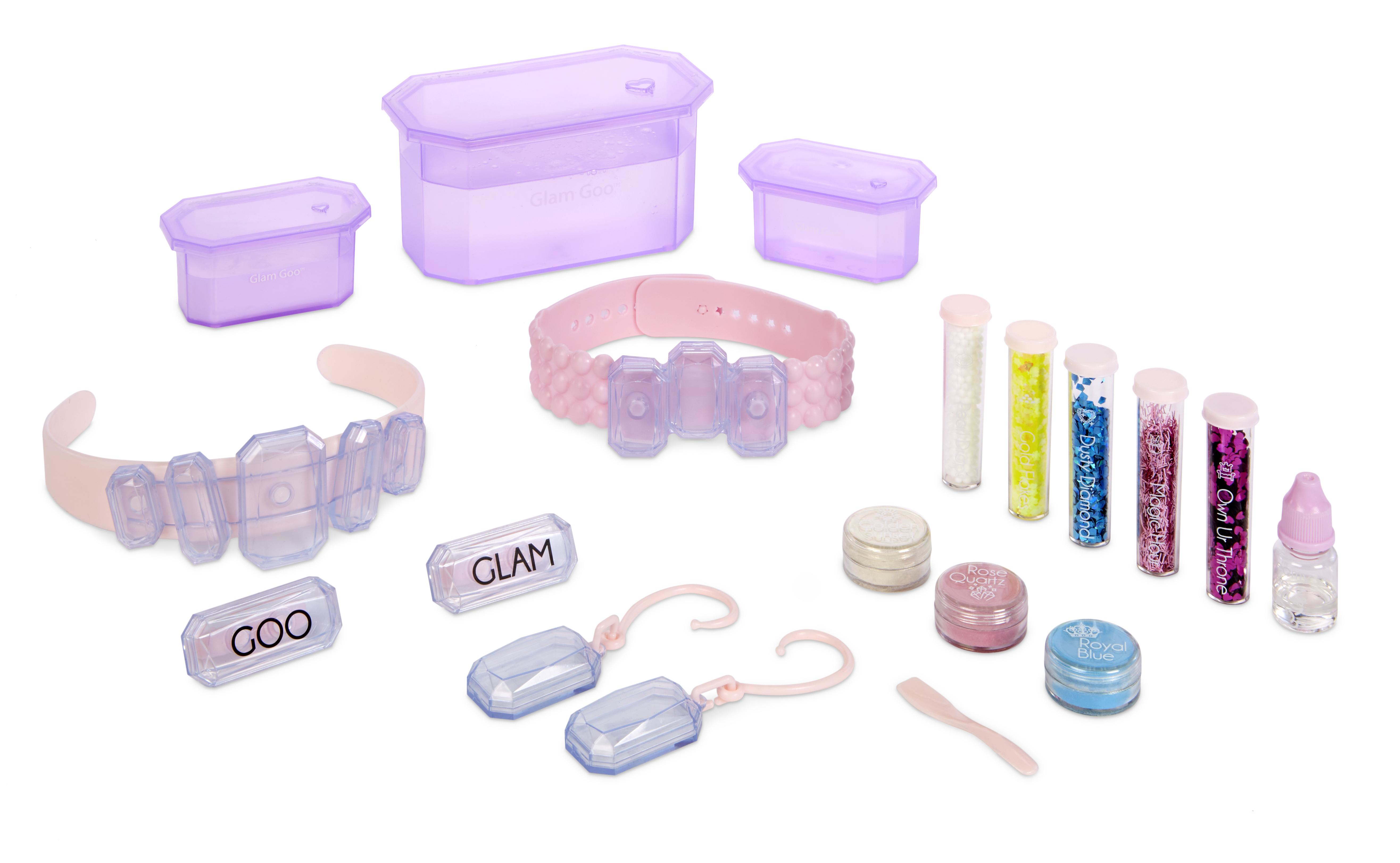 Contenido del kit Glam Goo: Joyas, accesorios y recipientes. Dominan los colores rosa y transparente.