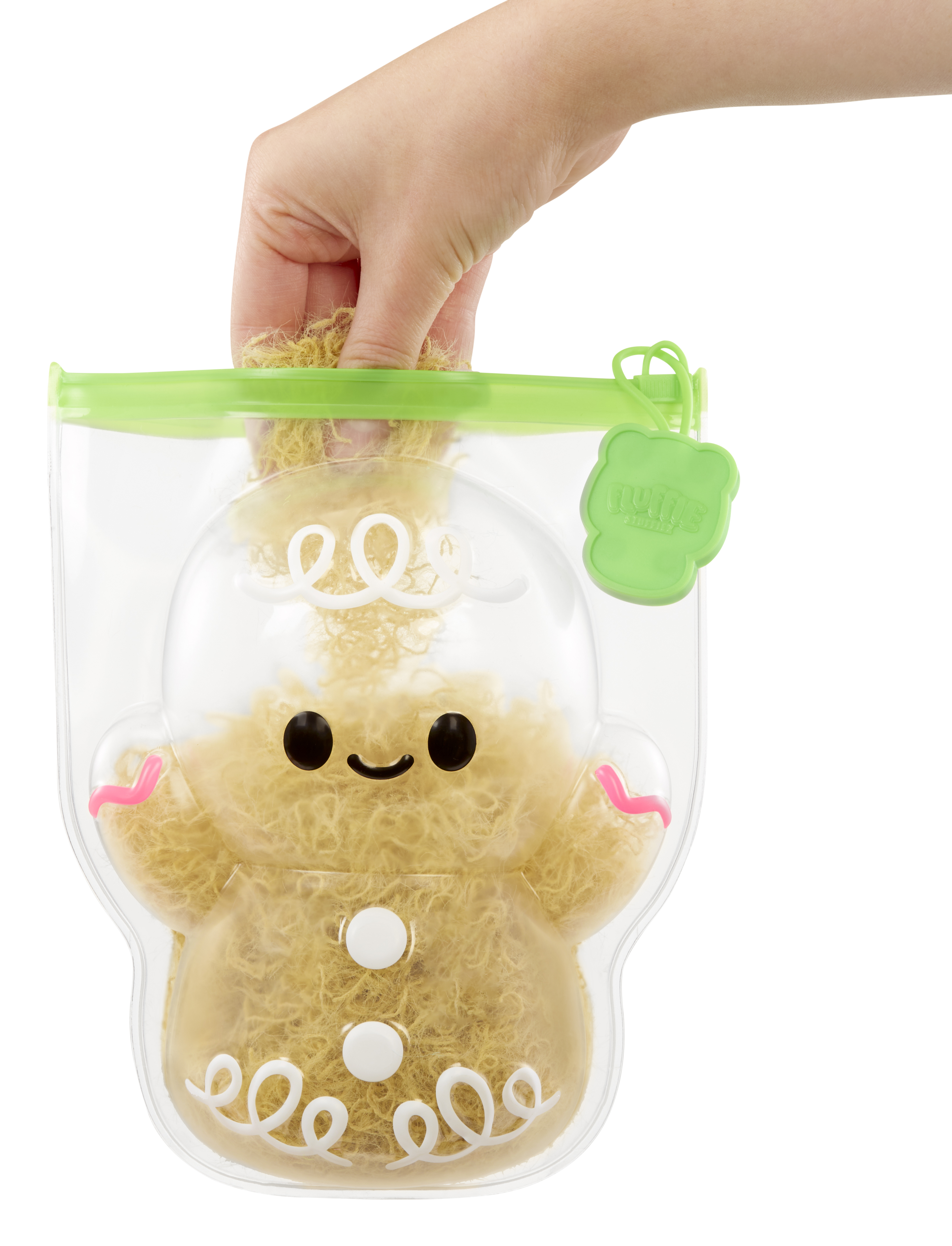 Dłoń trzymająca zabawkę piernikowego ludzika w przezroczystej torbie z zielonym zamkiem błyskawicznym.