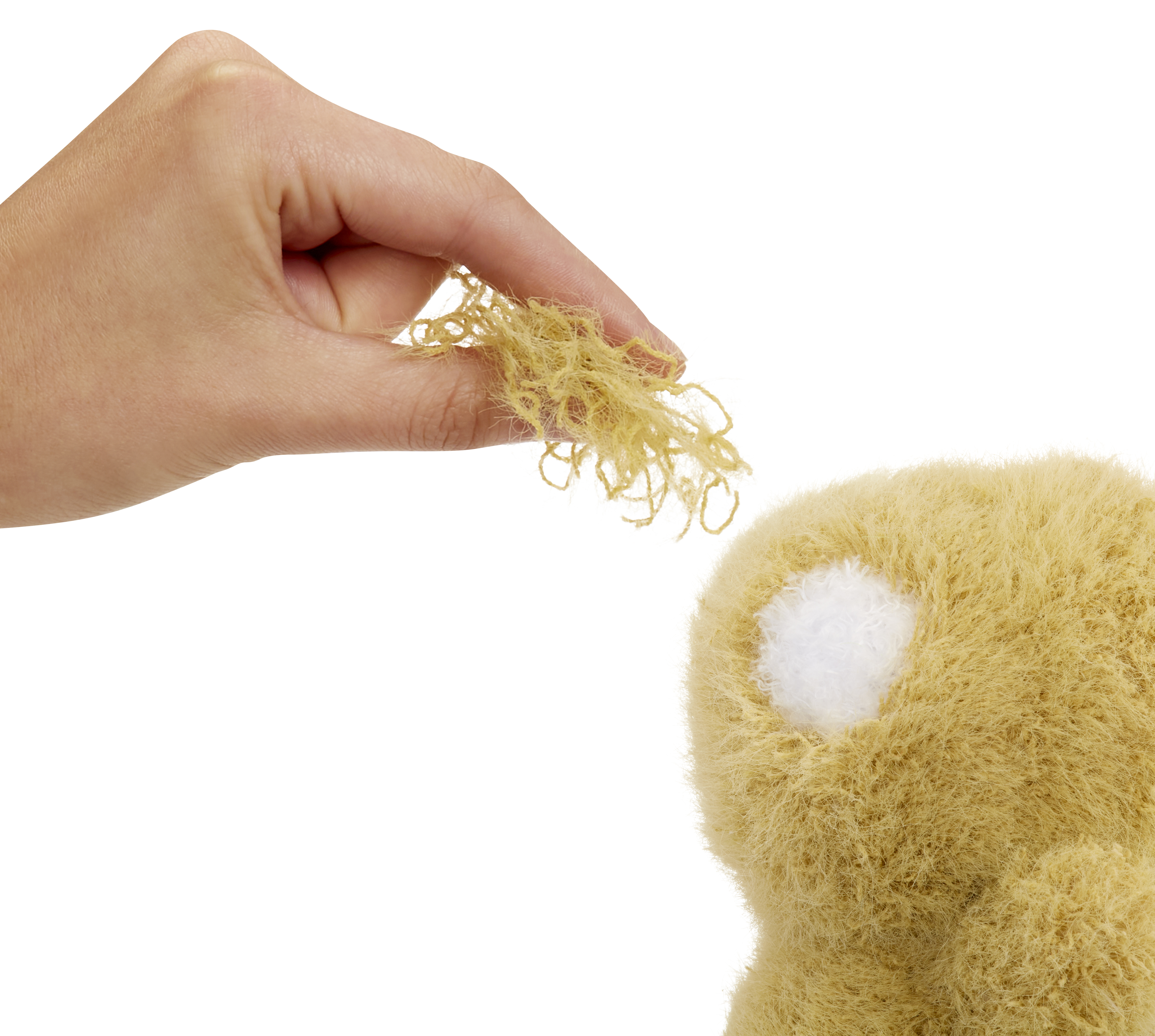 Dłoń trzymająca niewielką ilość jasnobrązowego materiału w pobliżu puszystej zabawki.
