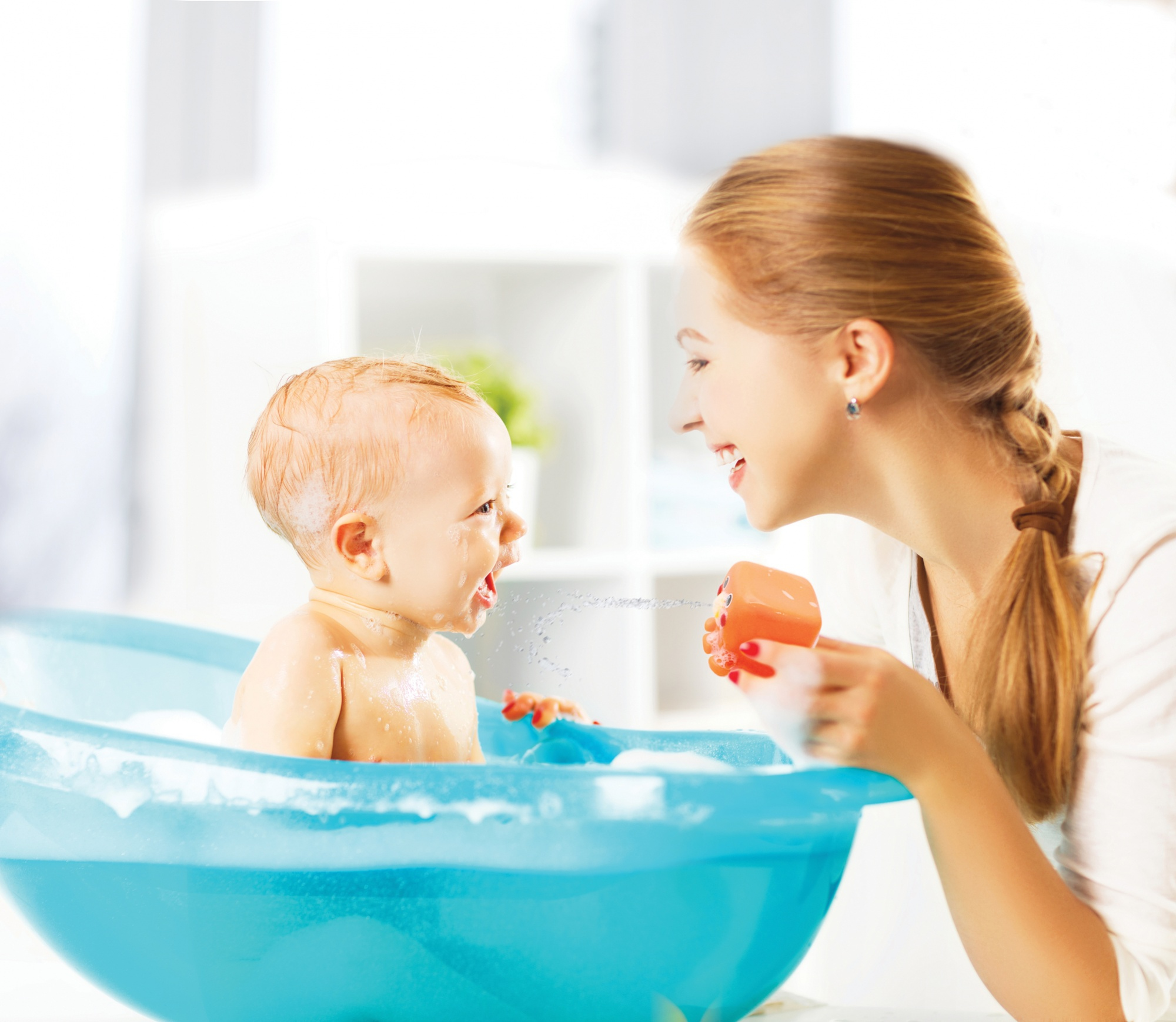 Madre e bambino in una vasca da bagno, che giocano con un giocattolo.