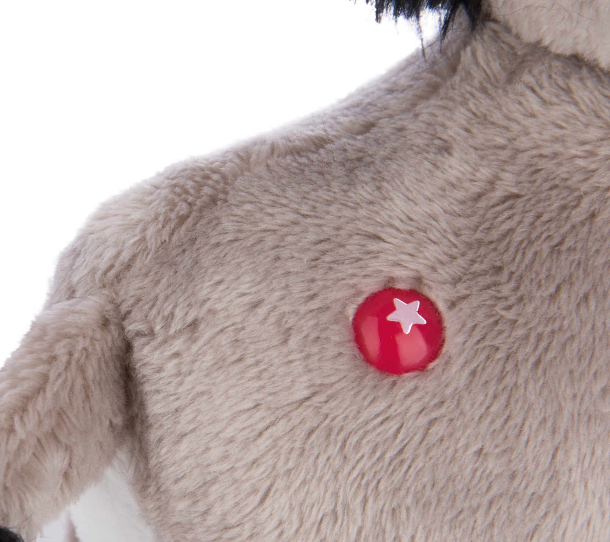 Zbliżenie pluszowego osła z szarym futrem. Czerwony guzik z białą gwiazdą jest na jego piersi.