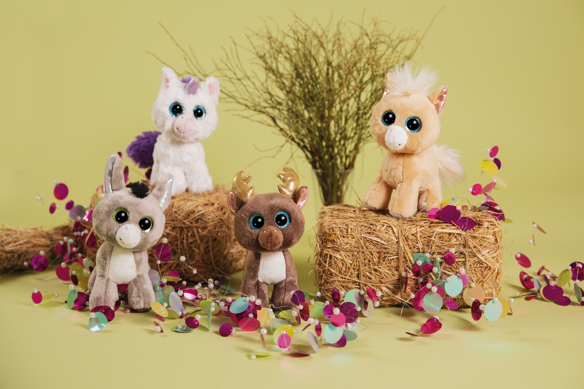 Cztery pluszowe zwierzęta na sianie. Osioł, jednorożec, jeleń i kucyk. Zielone tło.