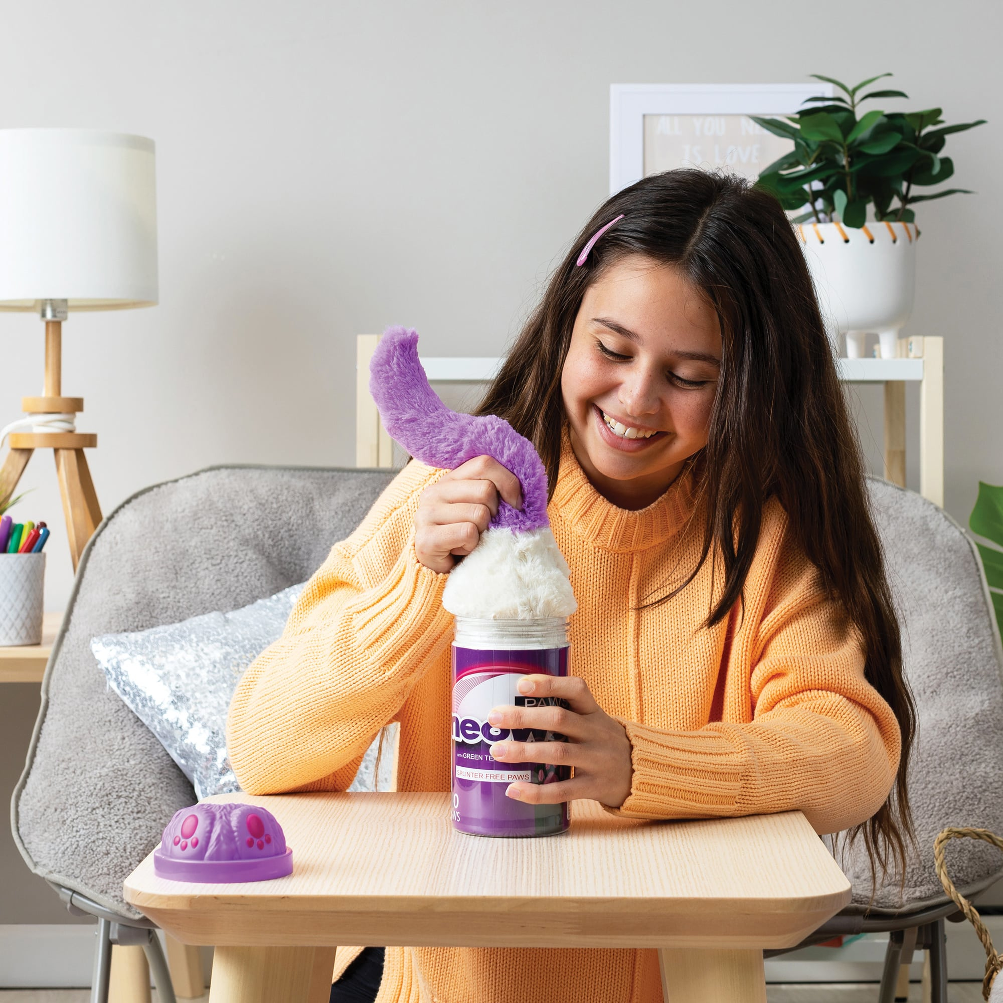 Dziewczyna otwiera puszkę z zabawką, z której wychodzi fioletowa zabawka.