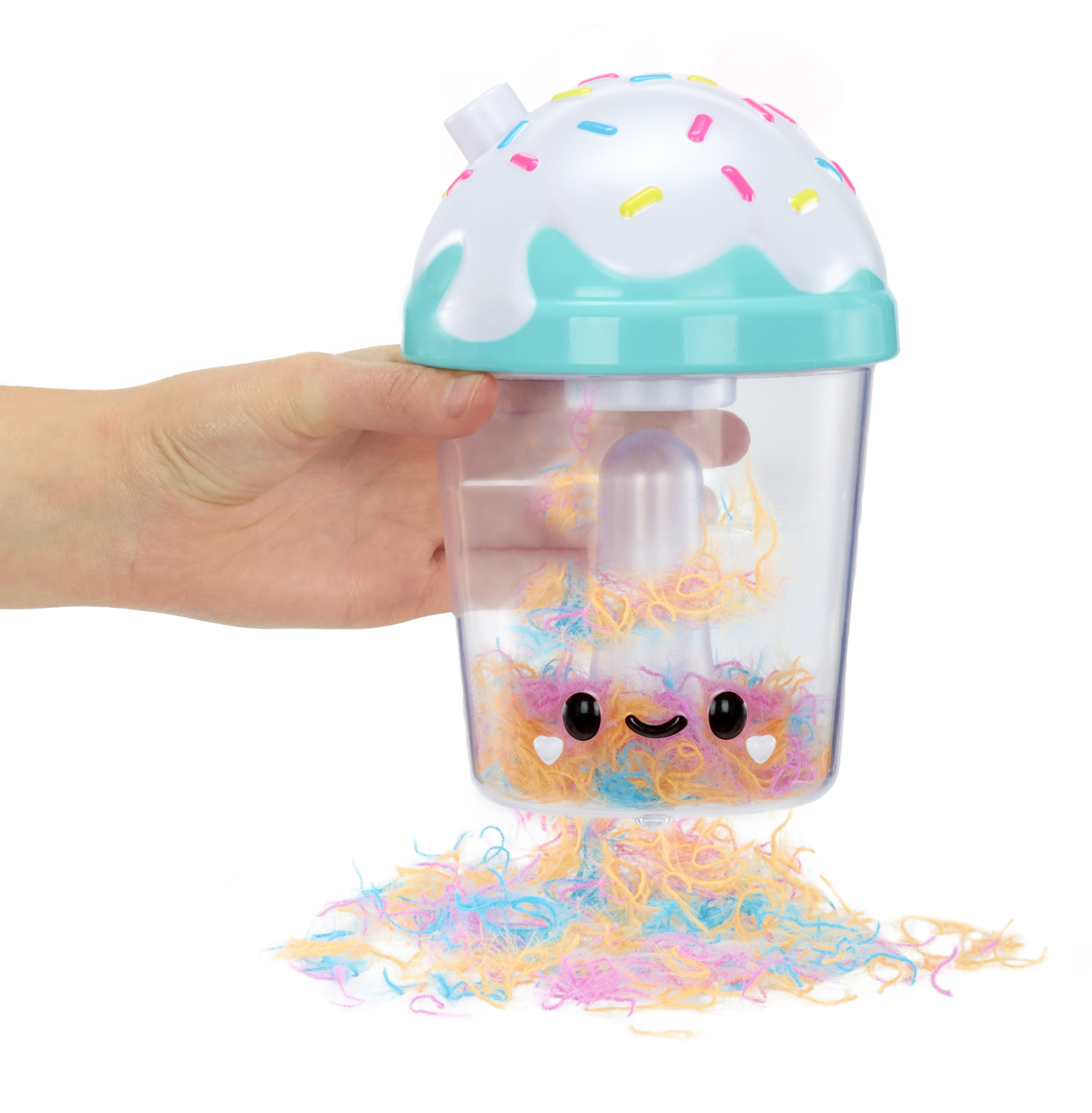 Mano che tiene una tazza giocattolo. La tazza ha una faccia sorridente e un ripieno colorato. Sfondo bianco.