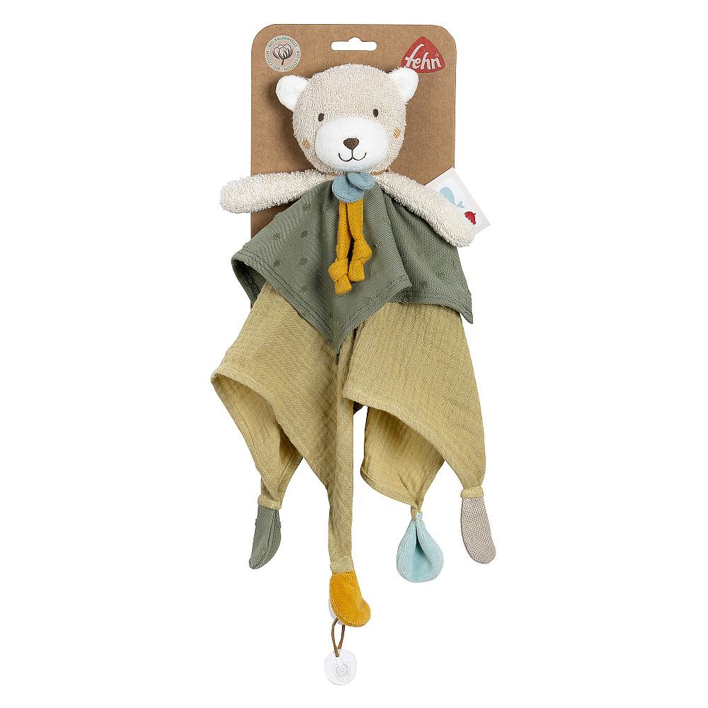 Zabawkowy miś z tkaniną, metką i kolorowymi załącznikami. Umieszczony na brązowej powierzchni.