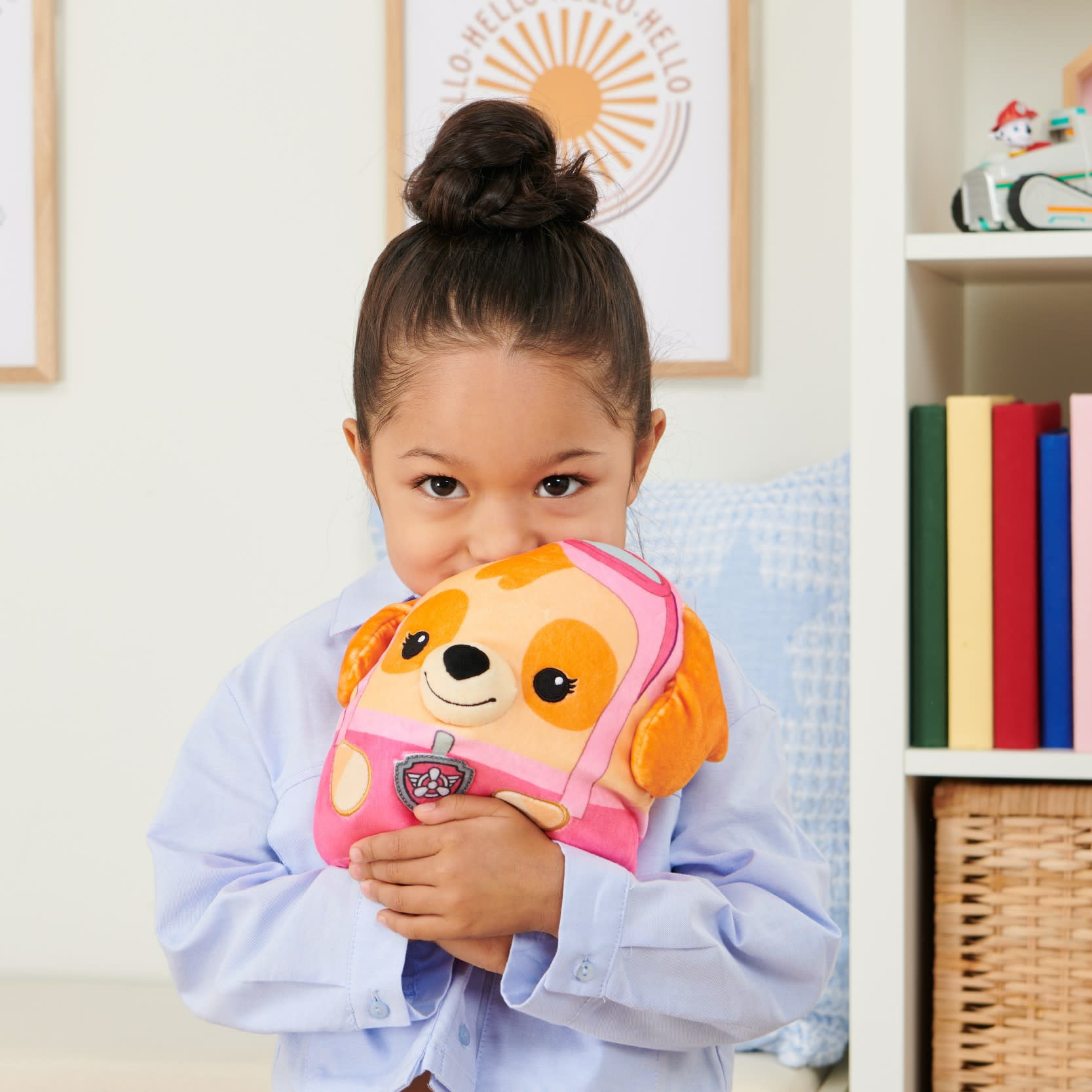 Una bambina che tiene in mano un peluche rosa con un disegno di cucciolo, davanti al suo viso.