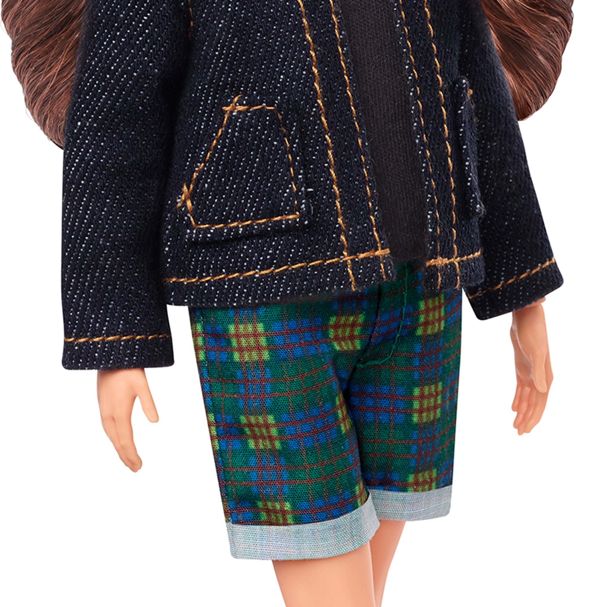 Lalka w dżinsowej kurtce, czarnym topie i kraciastej szortach. Brązowe włosy i jasna skóra.