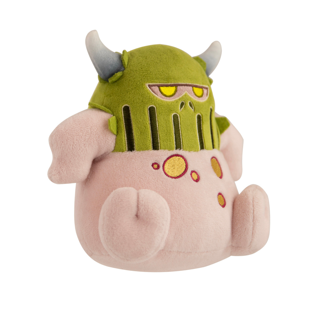 Peluche di una creatura con elmetto verde, corpo rosa, corna e macchie gialle. Sfondo bianco.