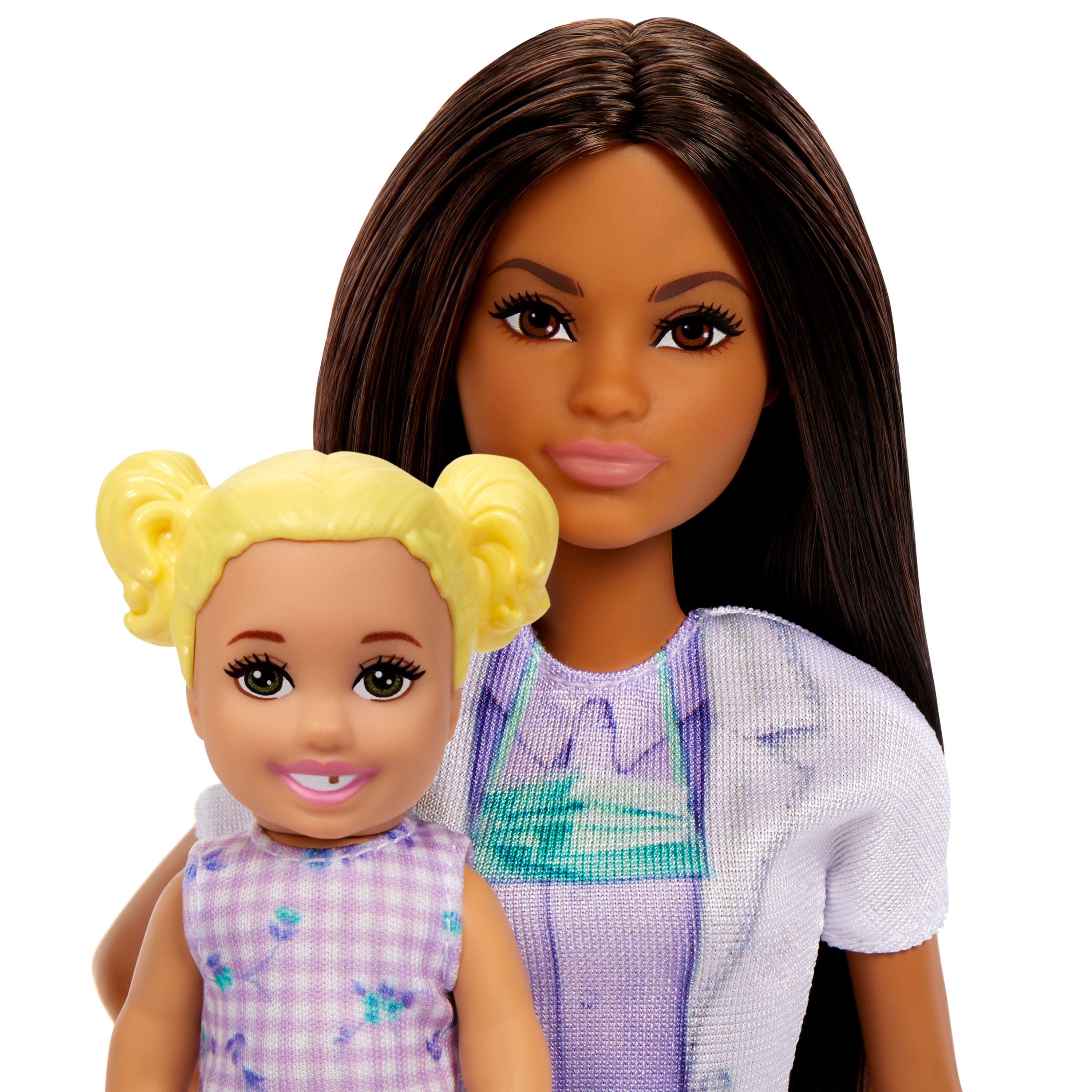Eine Barbie-Puppe mit langen braunen Haaren und ein lächelndes Kleinkind mit blonden Zöpfen vor ihr.