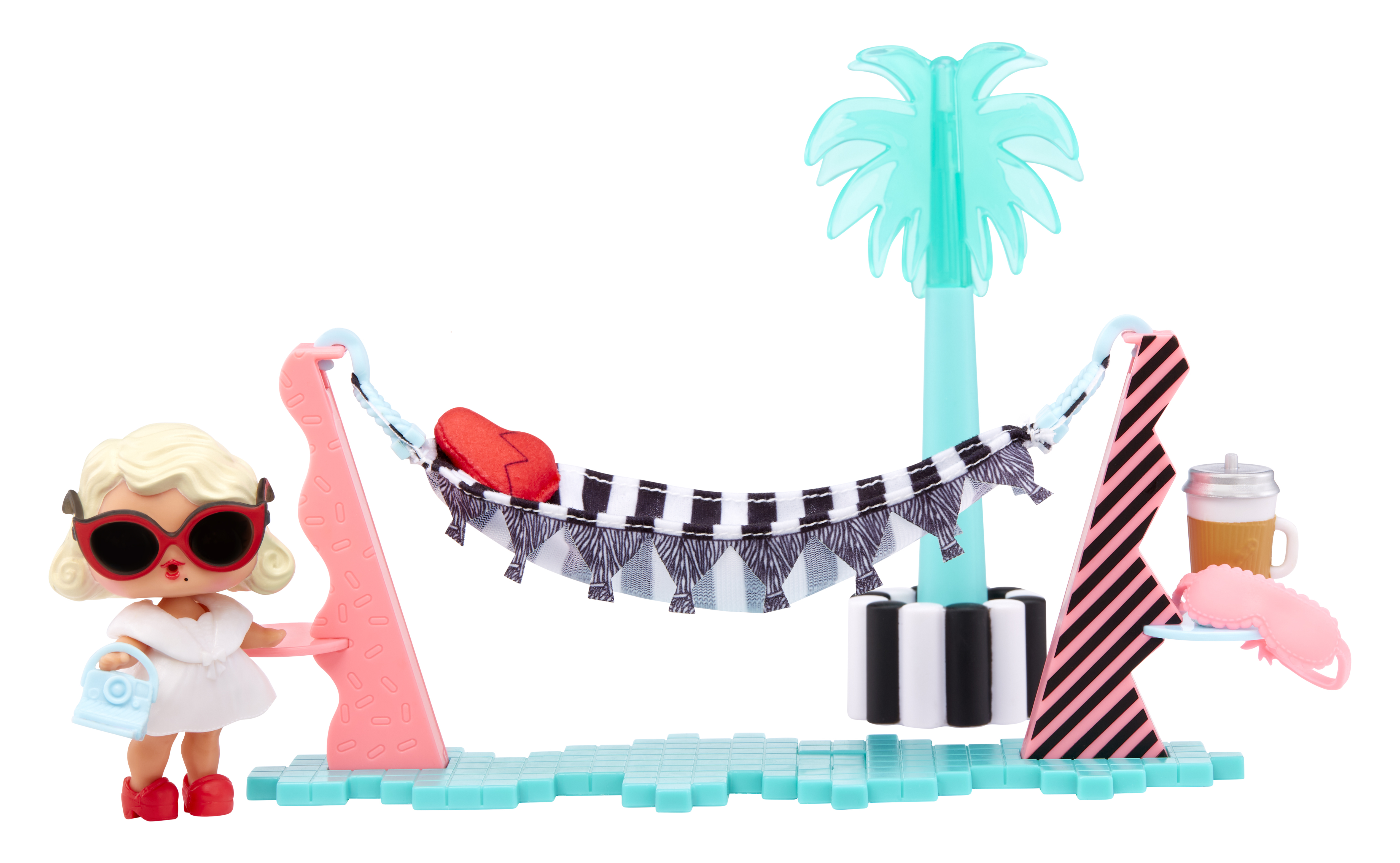 Lalka w okularach przeciwsłonecznych i białej sukience stoi w pobliżu hamaka z palmą i akcesoriami.