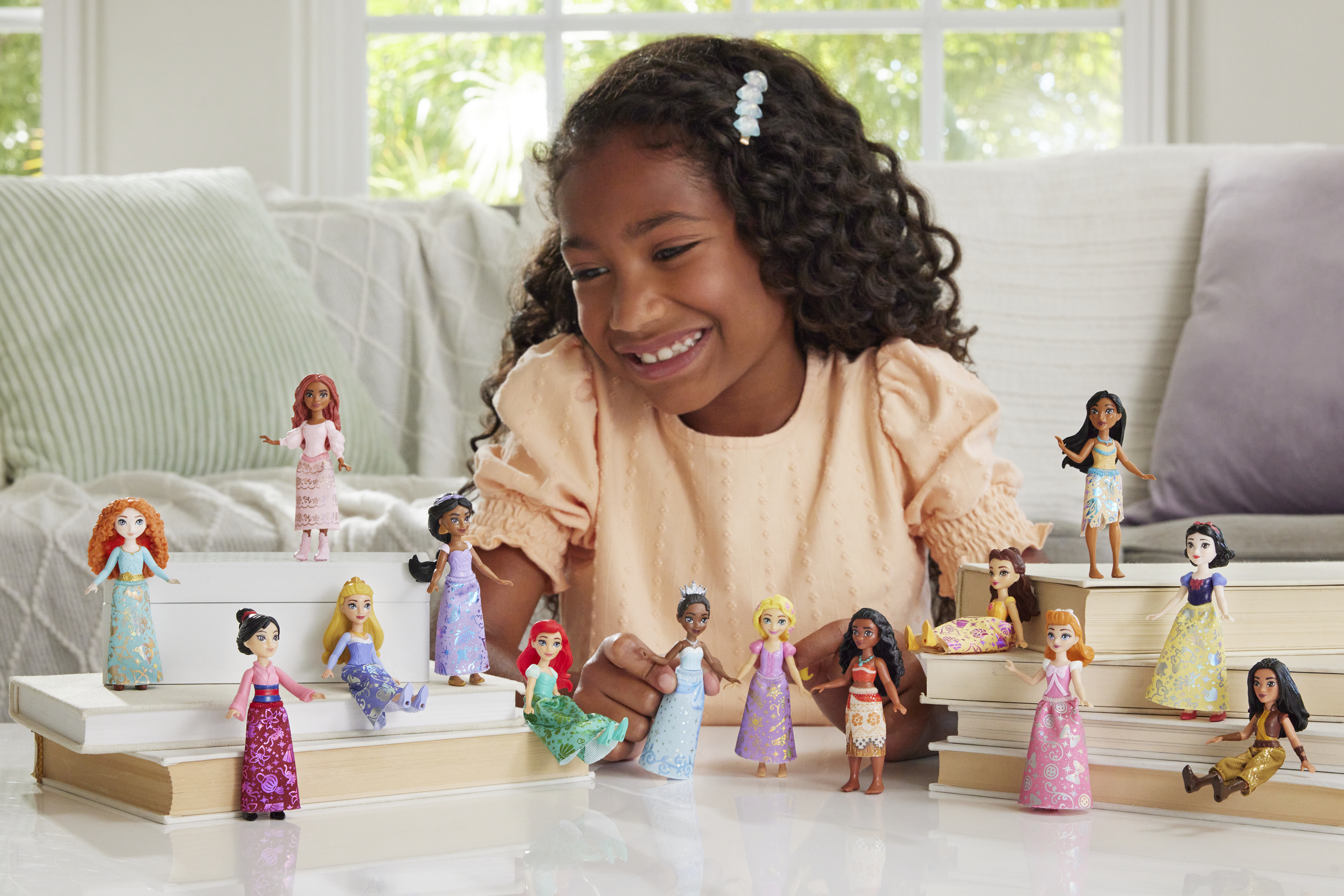 Mädchen lächelt über Disney-Prinzessinnen-Puppen auf Büchern.
