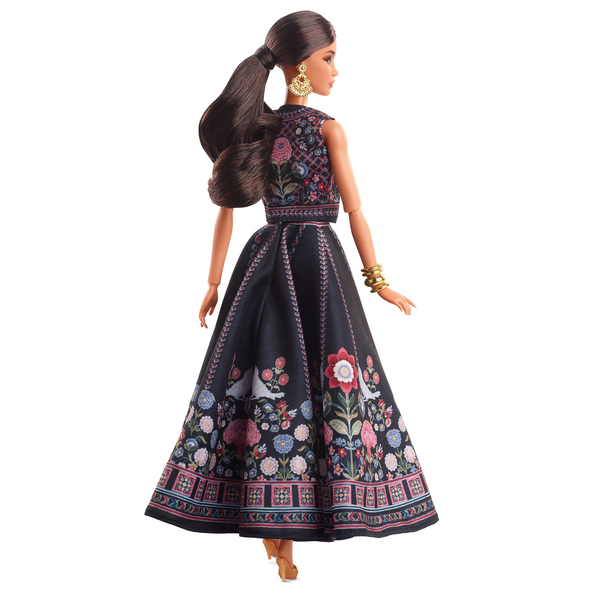 Eine Barbie-Puppe trägt ein schwarzes Kleid mit floraler Stickerei. Die Puppe hat dunkles Haar.
