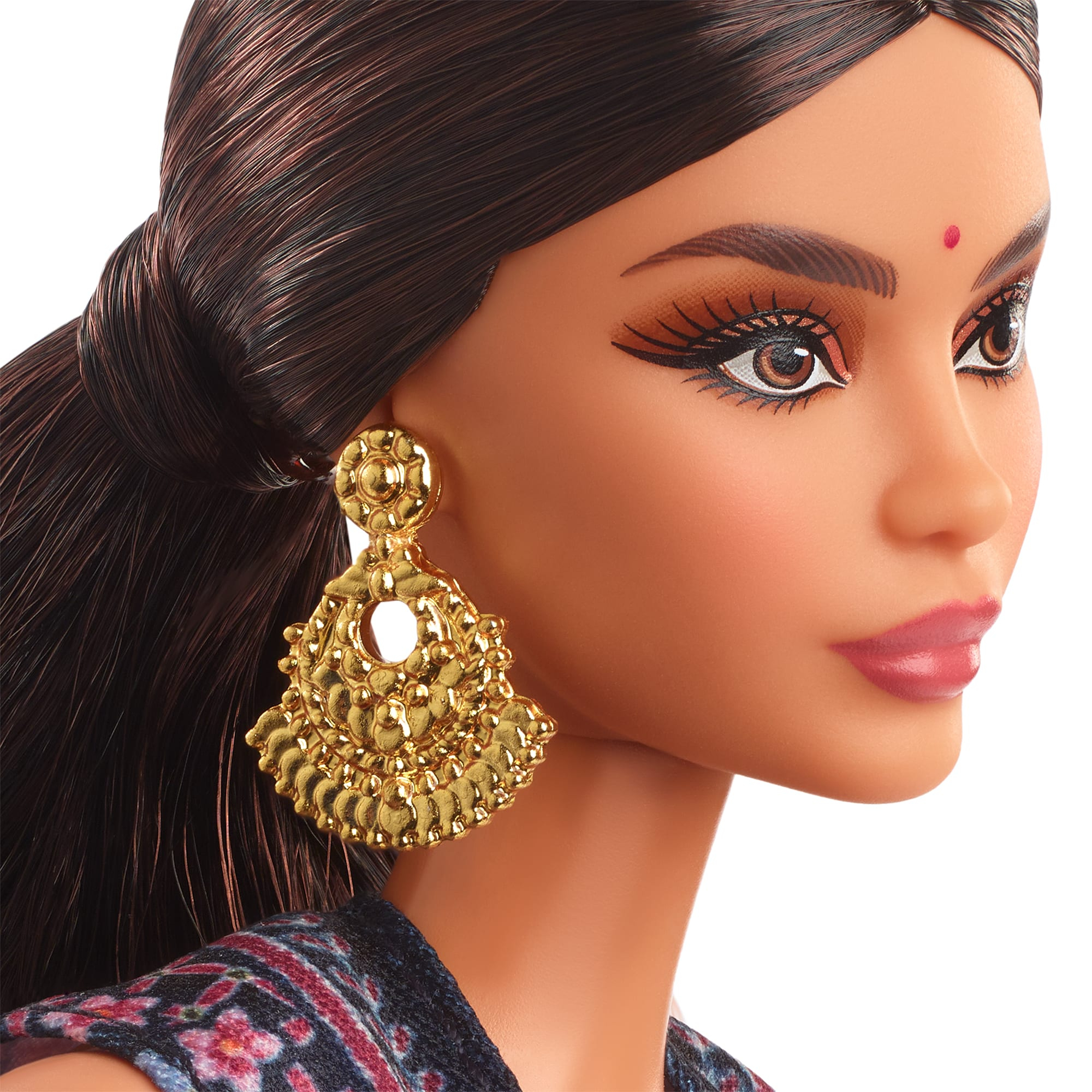 Nahaufnahme des Gesichts einer Barbie-Puppe. Sie hat dunkles Haar, goldene Ohrringe und einen roten Bindi.
