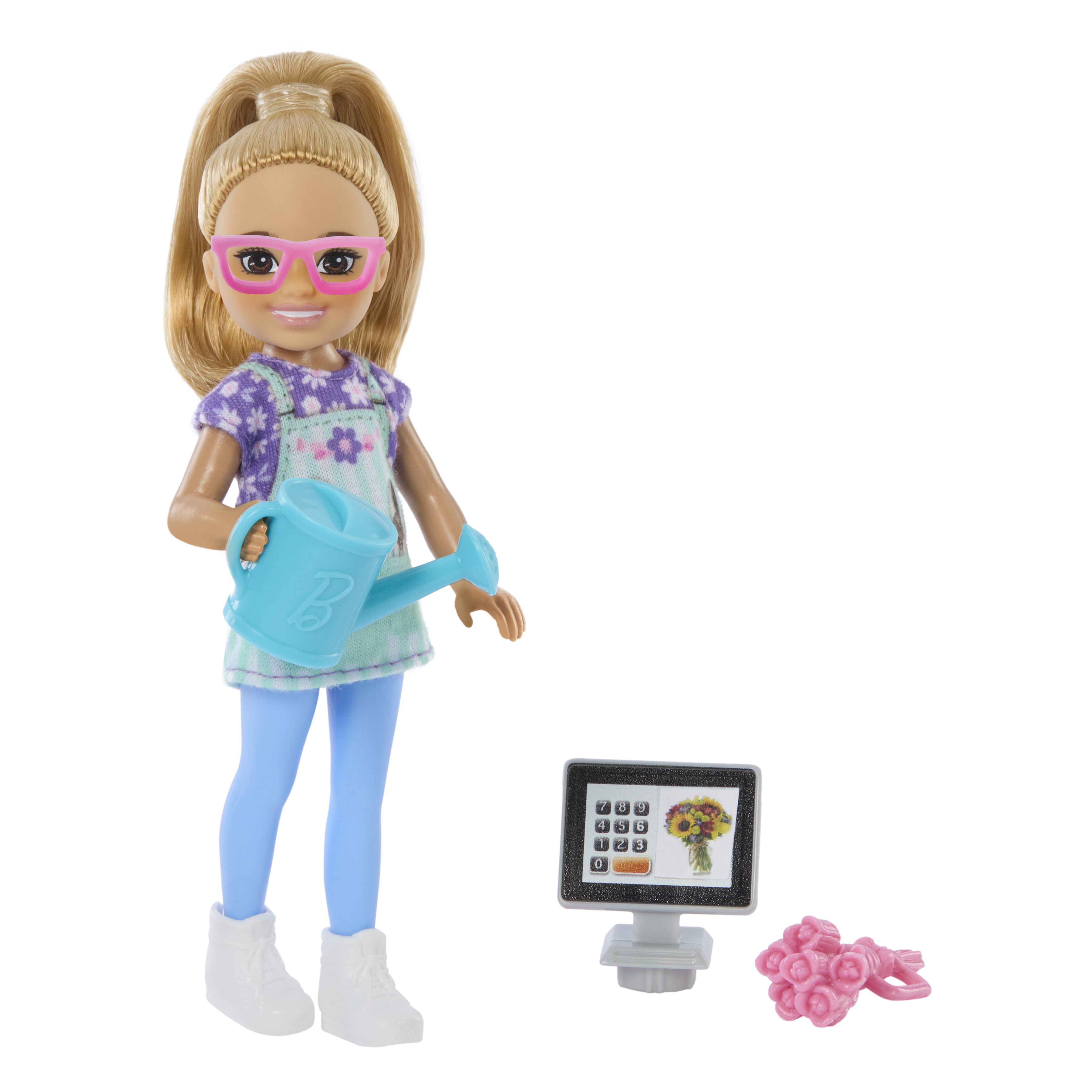 Blonde Puppe mit Brille, die eine blaue Gießkanne hält, in der Nähe eines Monitors mit Blumen und einem Strauß.
