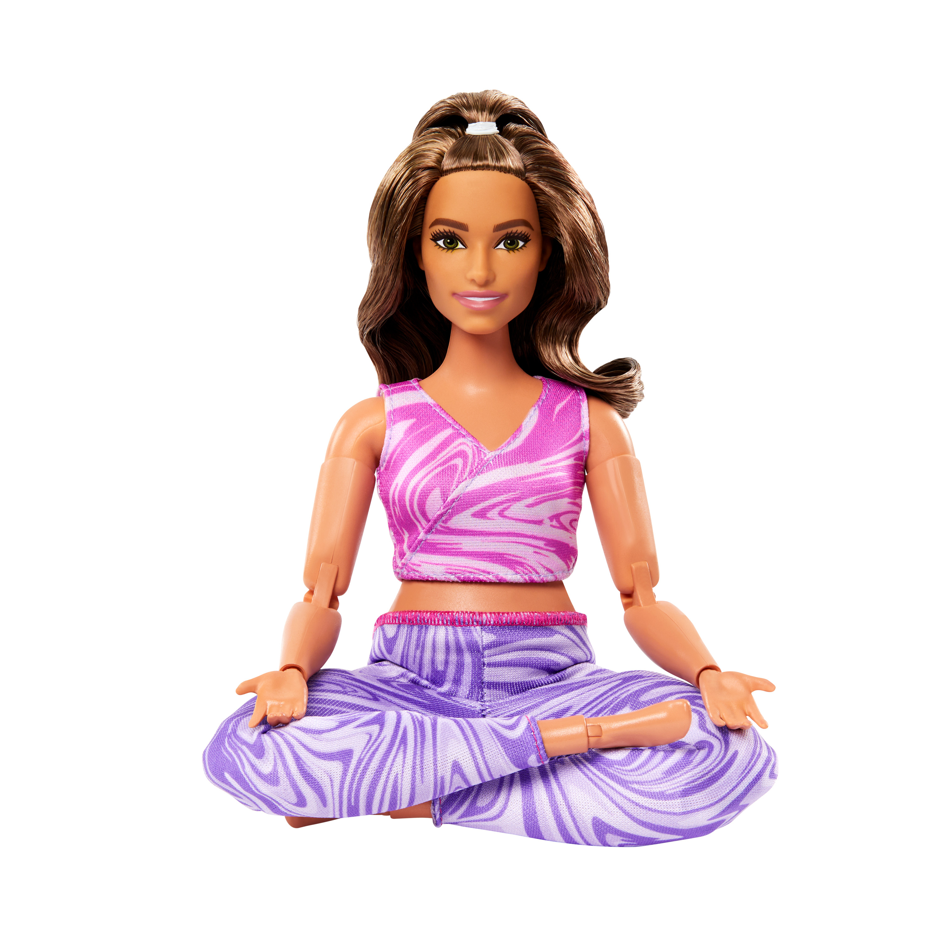 Eine Barbie-Puppe in einer Yoga-Pose, trägt ein rosa-lila Outfit, sitzt auf dem Boden.