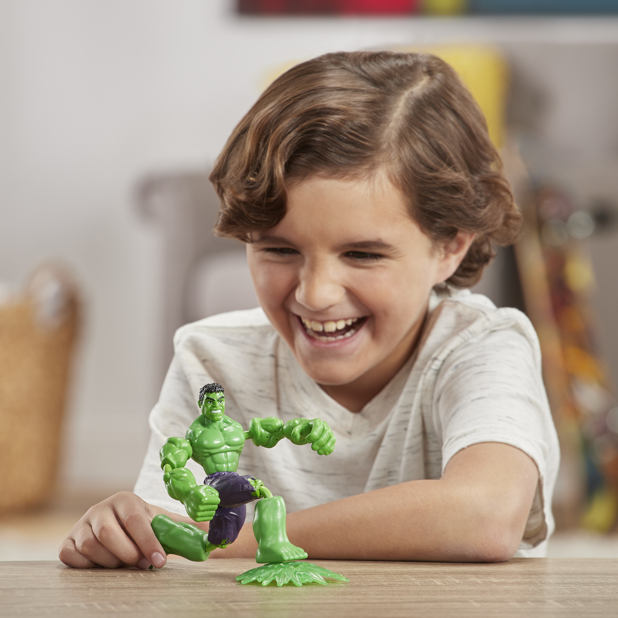 Ragazzo che gioca con un giocattolo di Hulk. Il ragazzo sorride. Hulk è verde e viola.