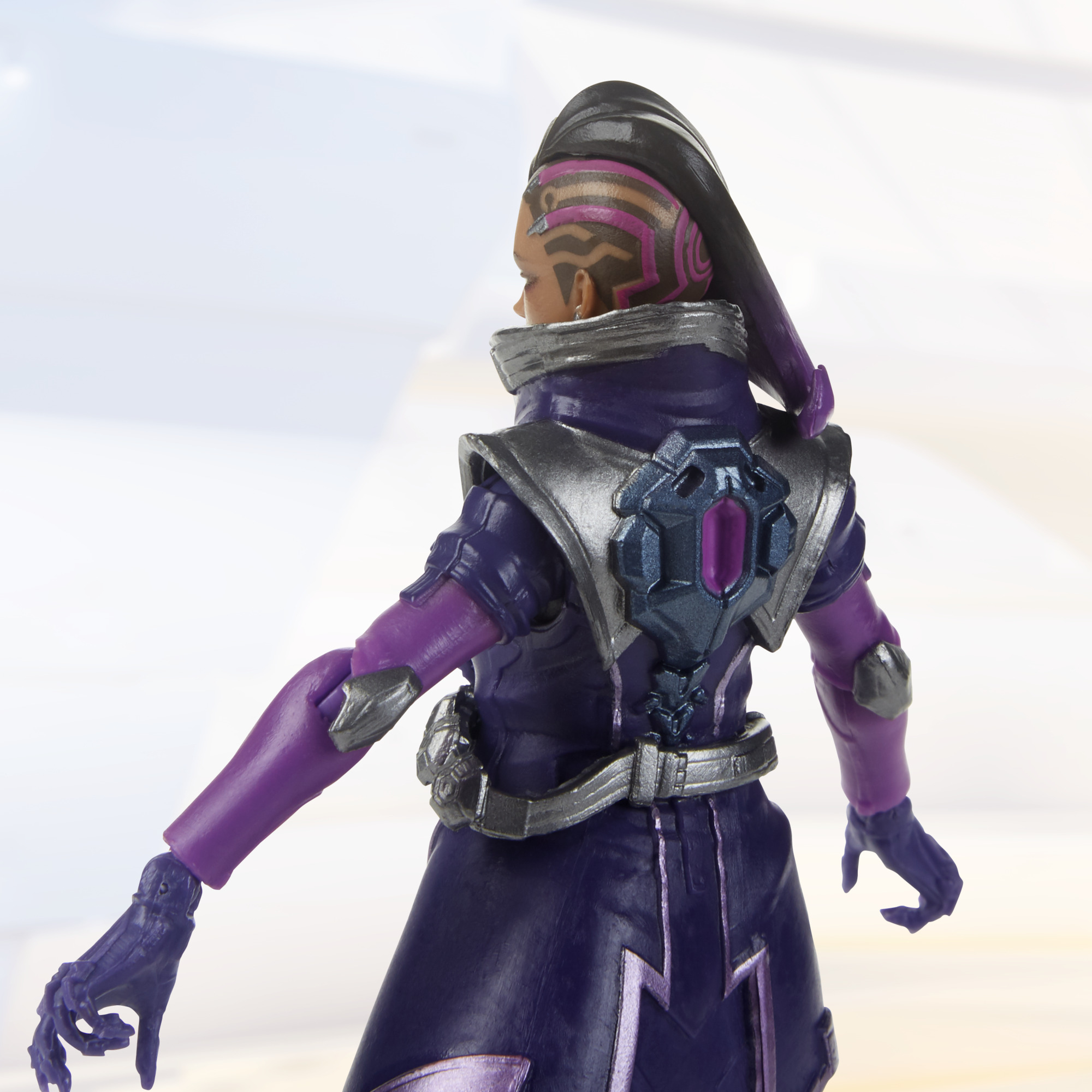 Una figura di un personaggio di Overwatch, vista posteriore, in un completo viola e argento.
