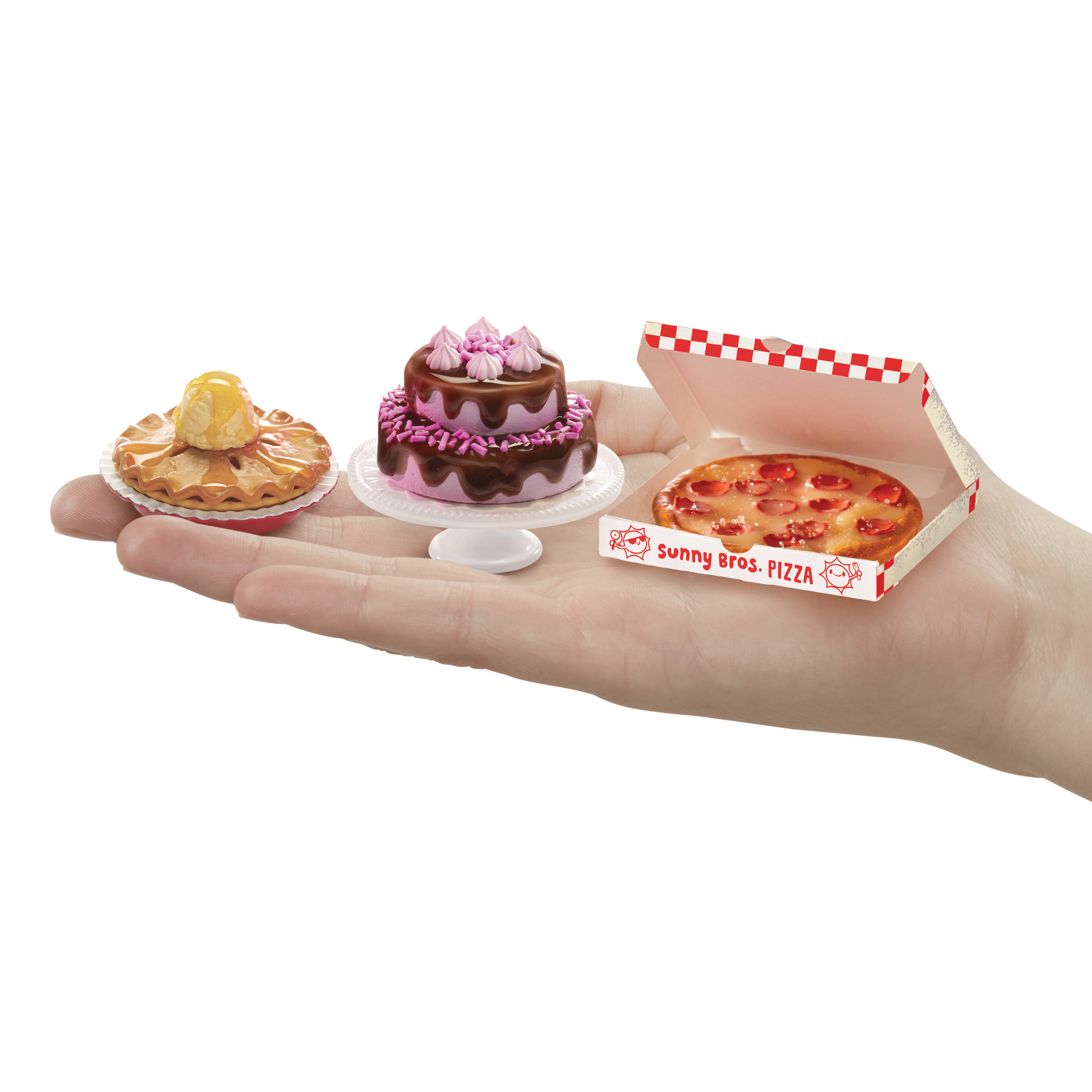 Miniature di cibo: una torta, una torta e una pizza in una scatola. Sono su una superficie bianca.
