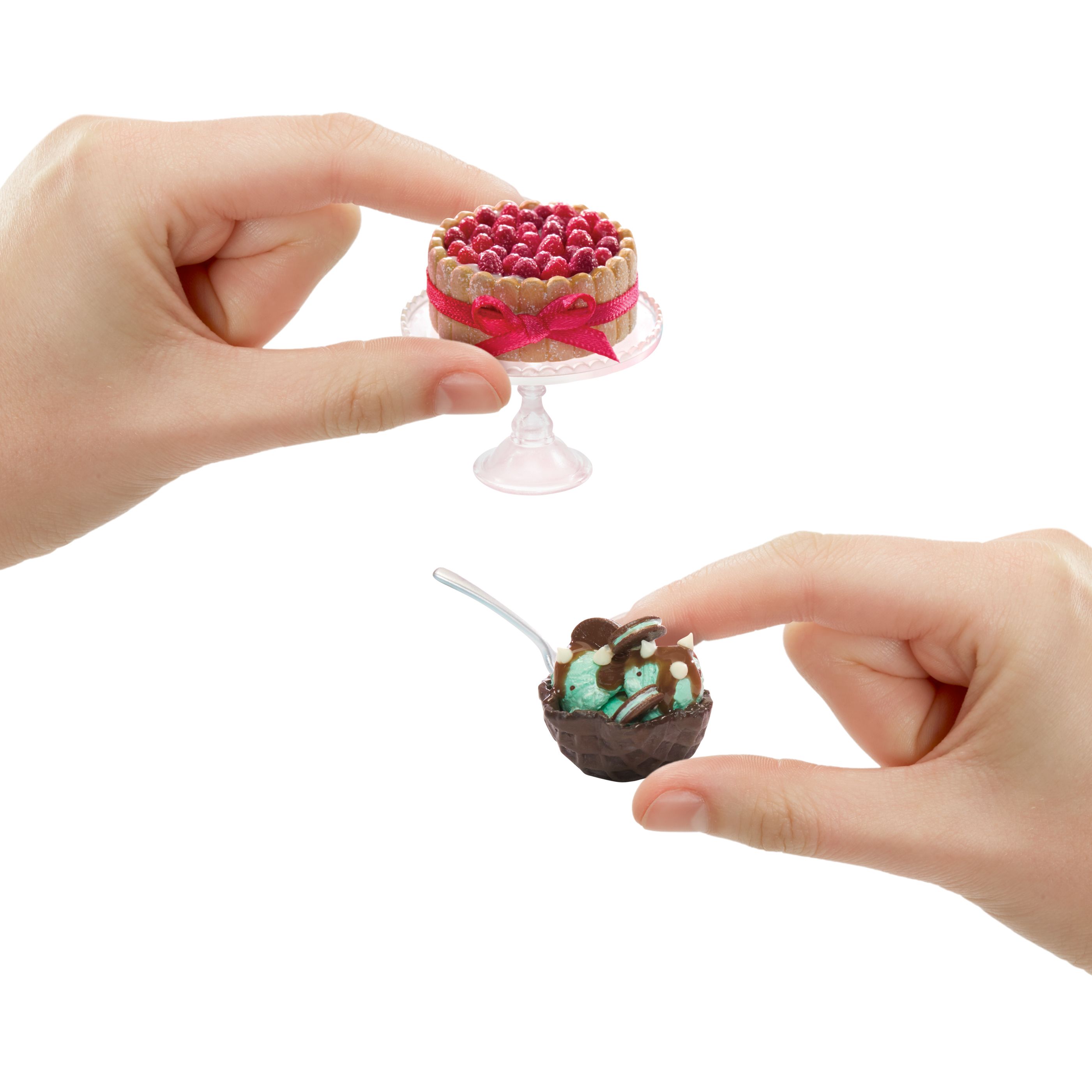 Mani che tengono torta in miniatura con lamponi e una ciotola con gelato e menta.