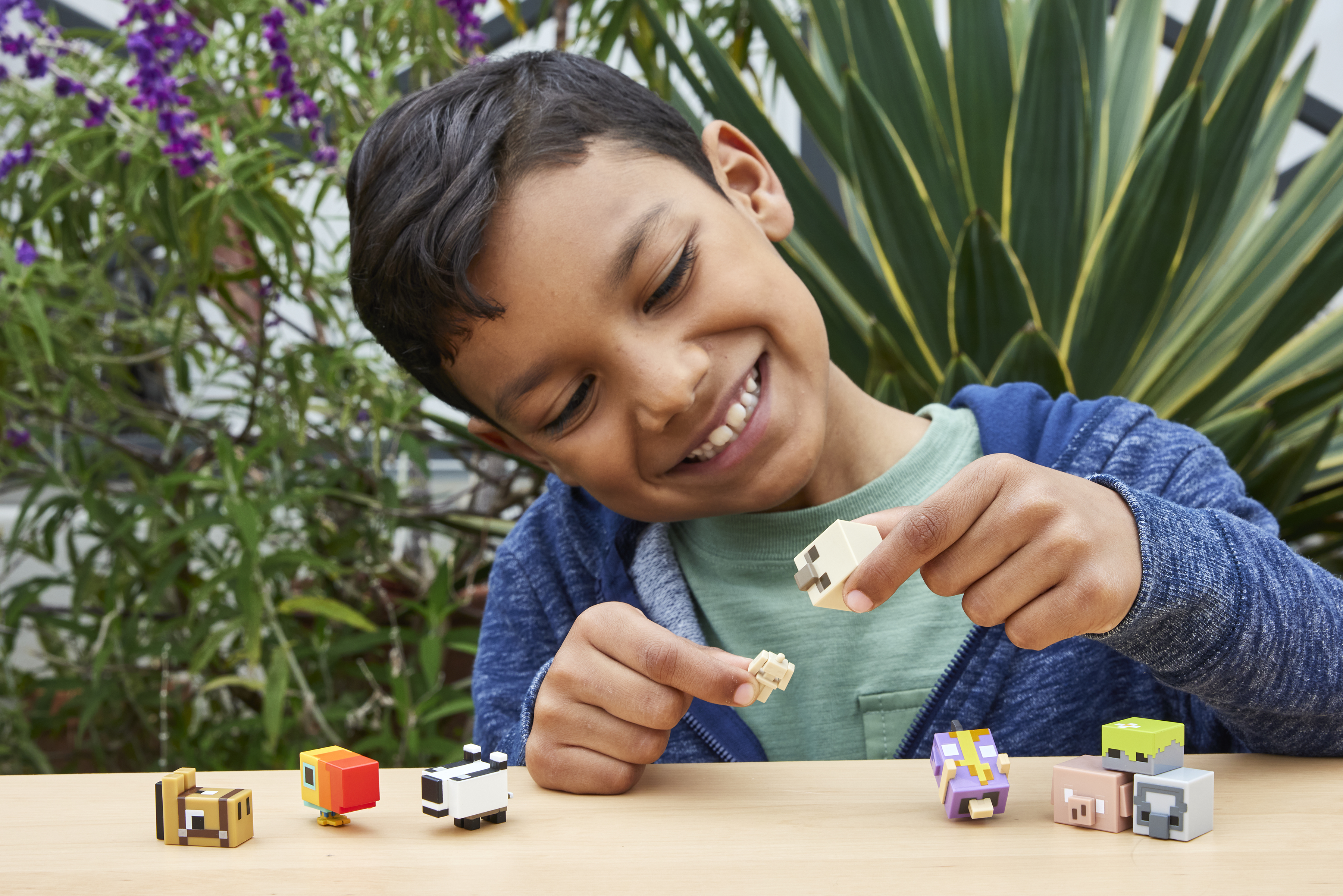 Chłopiec bawiący się figurkami Minecraft, uśmiechnięty.