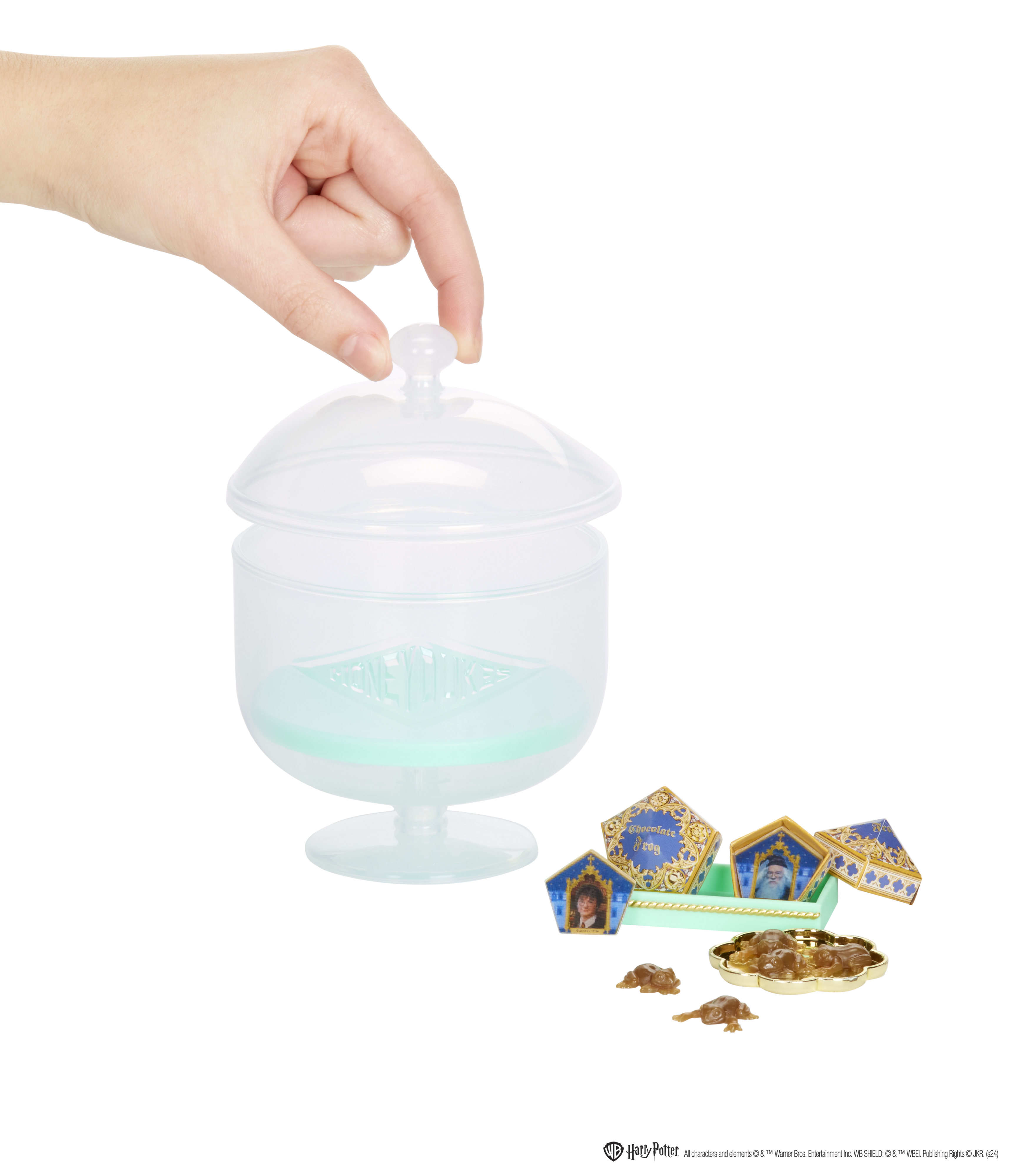 Ręka otwiera słoik z przezroczystą pokrywką nad tacką z pudełkami cukierków.