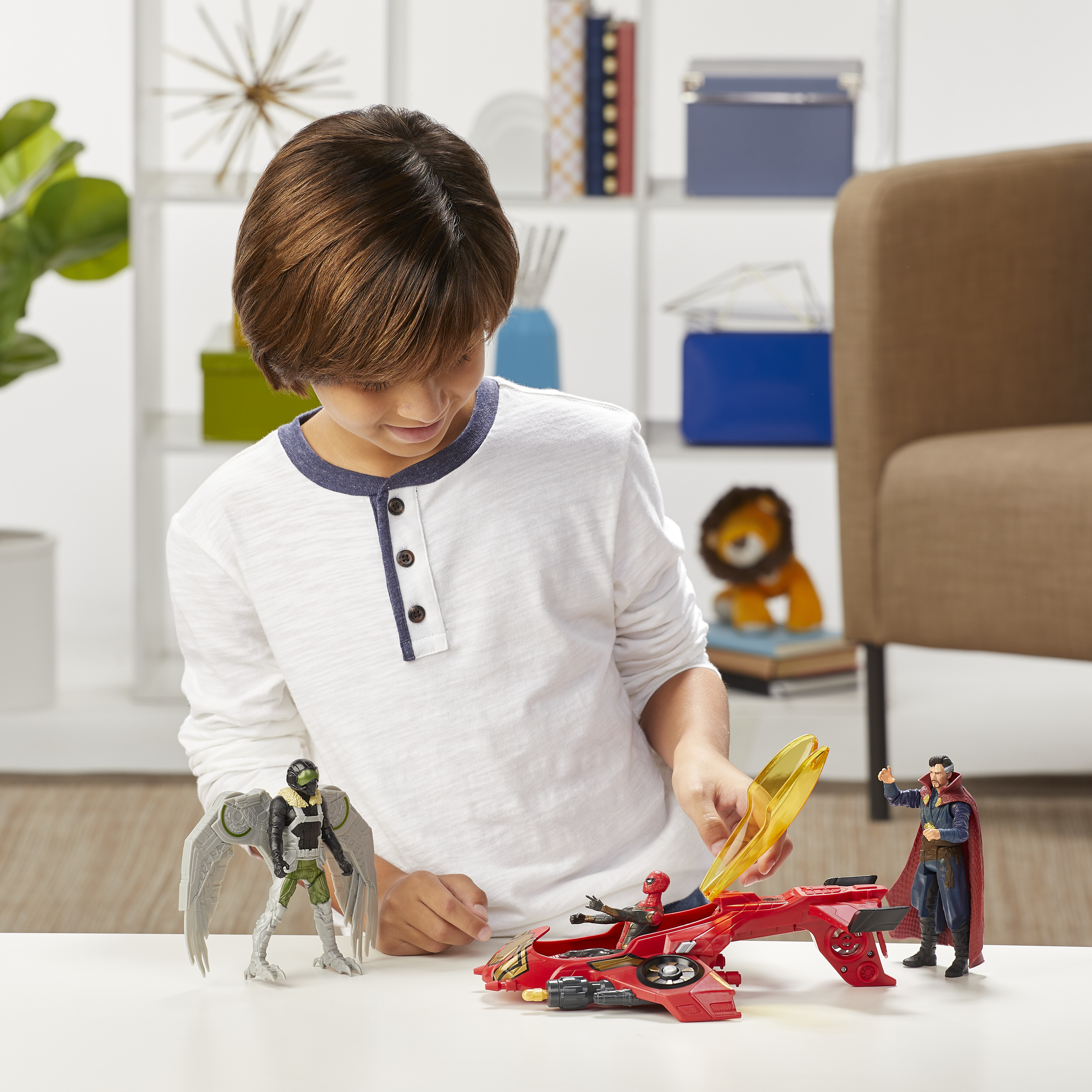 Un ragazzo gioca con action figure: un jet rosso, una figura verde e grigia e altri due personaggi.