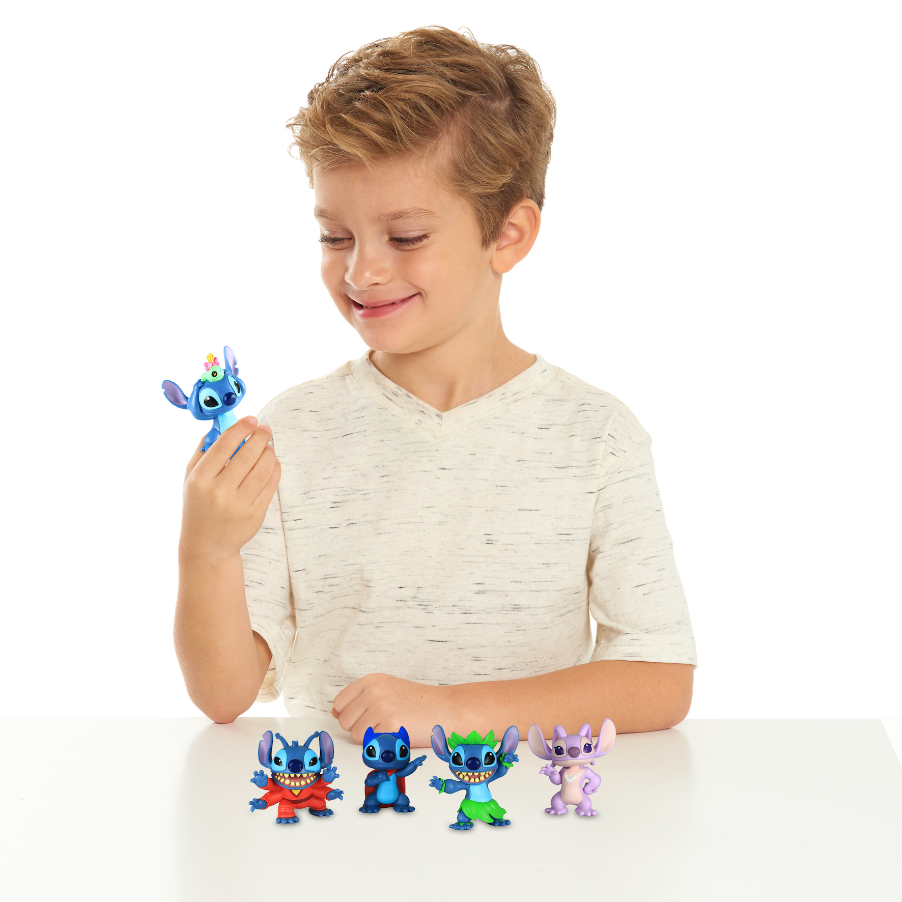 Un niño sostiene una figura azul de Stitch, otras cuatro en una mesa.