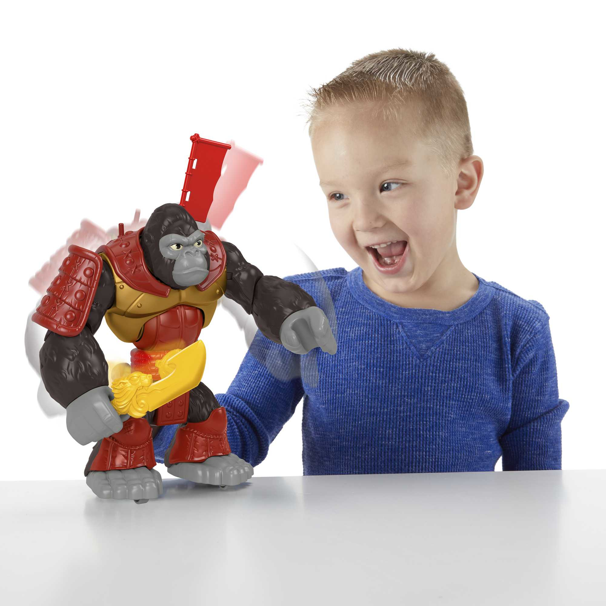 Un niño juega con un juguete de gorila con armadura. El niño sonríe y señala el juguete.
