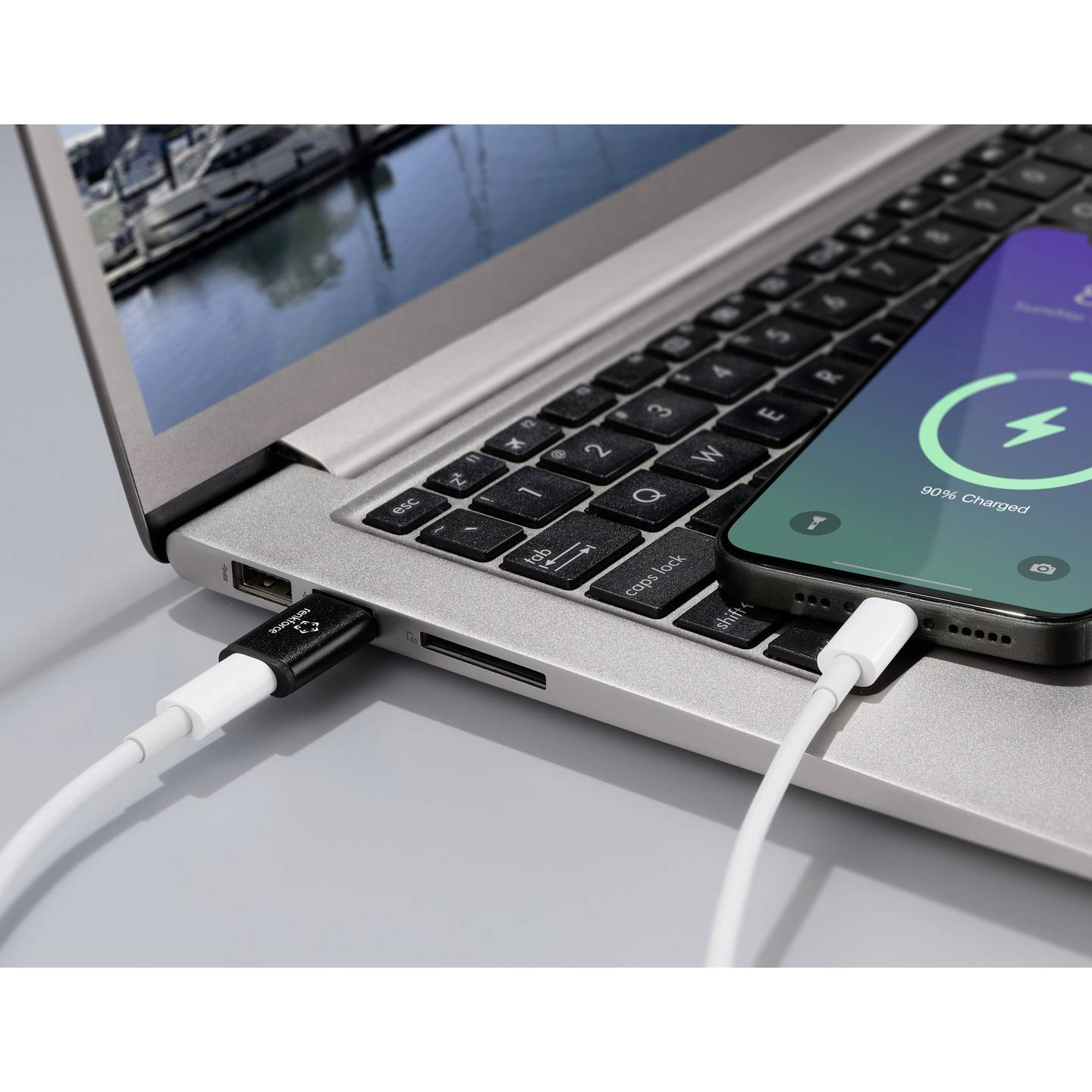 Un laptop e uno smartphone sono collegati con un adattatore USB e un cavo di ricarica.
