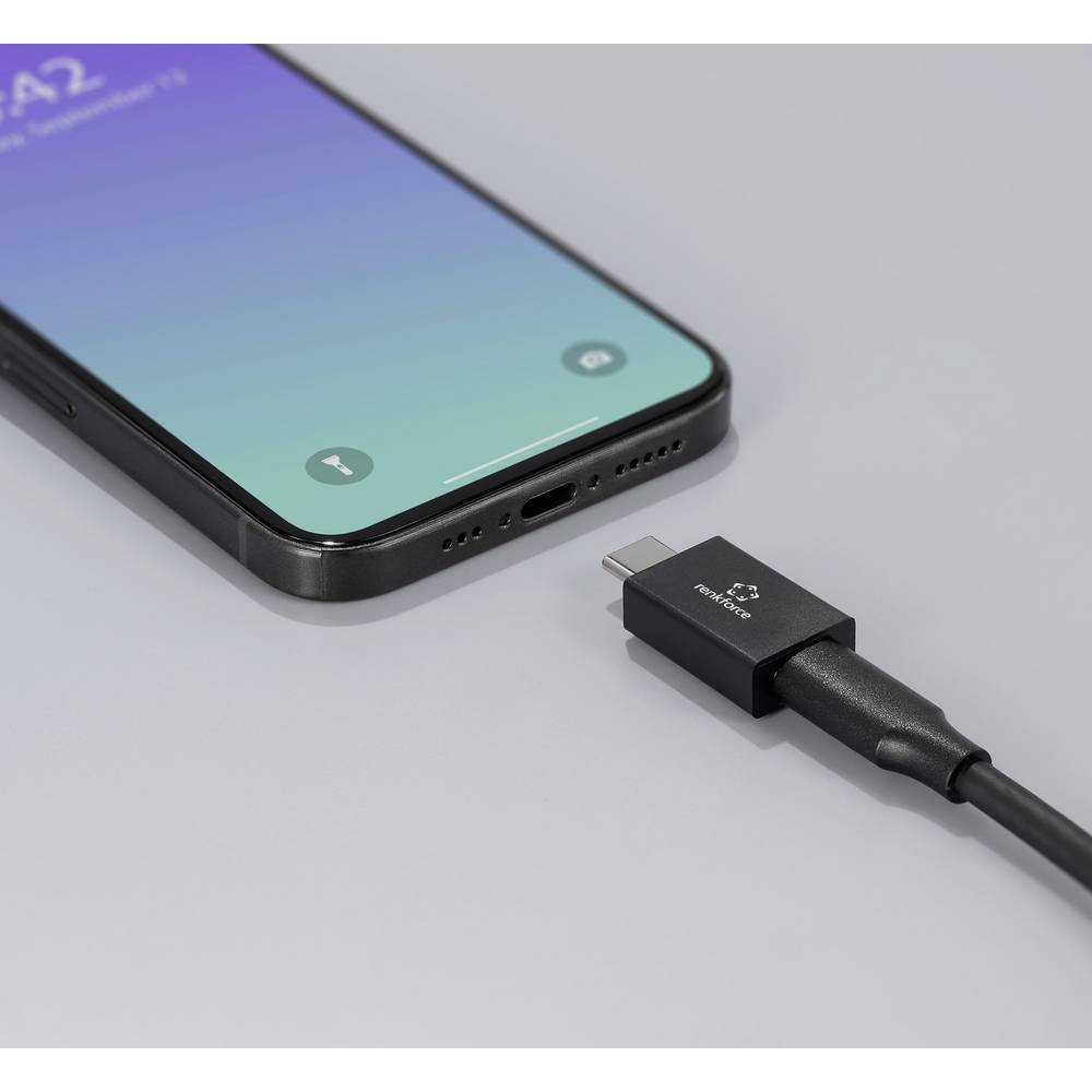 Uno smartphone con custodia nera e un cavo USB-C collegato, su una superficie grigia.