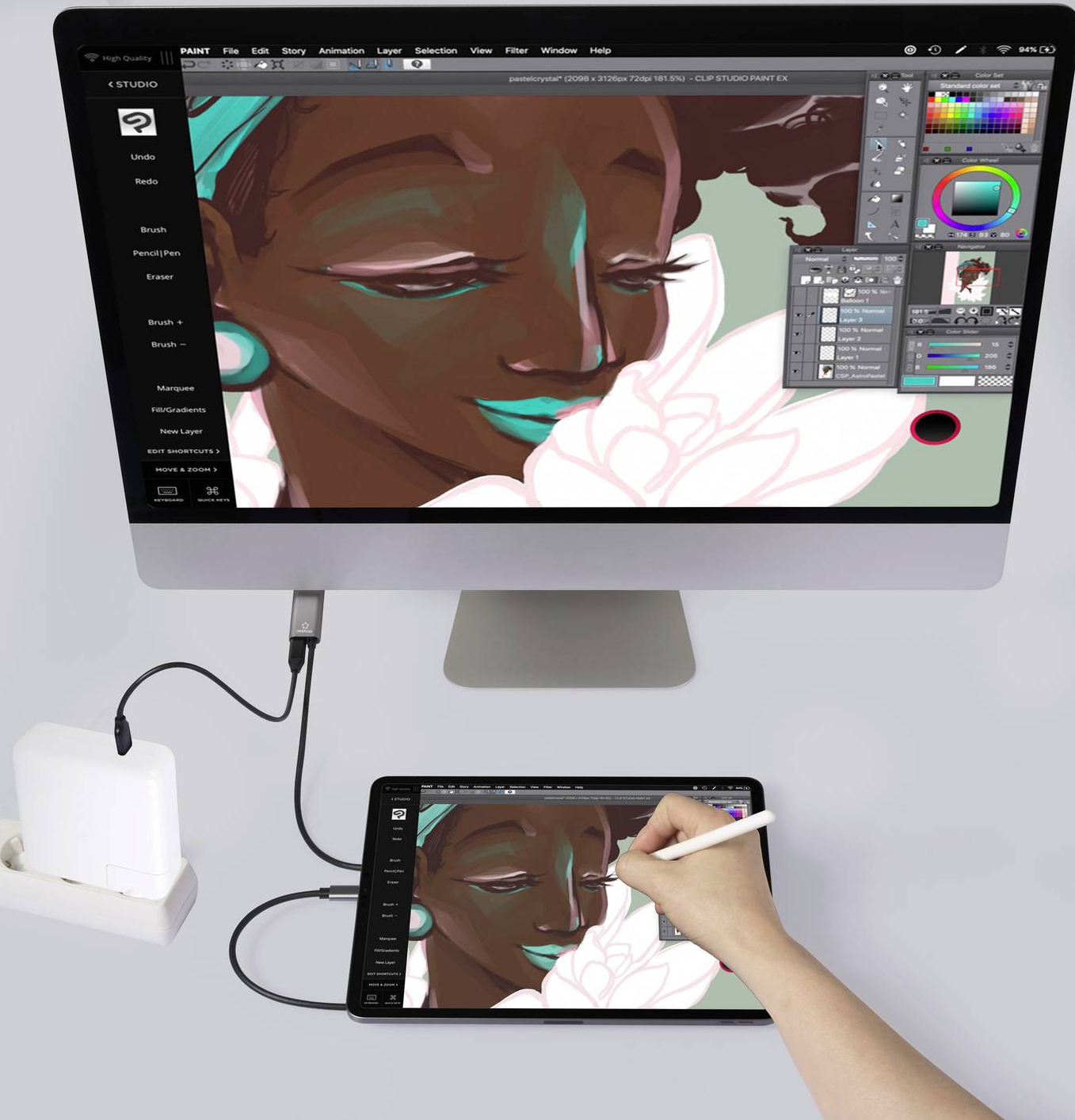 Artista digitale che utilizza un tablet e un computer, collegati tramite cavo.