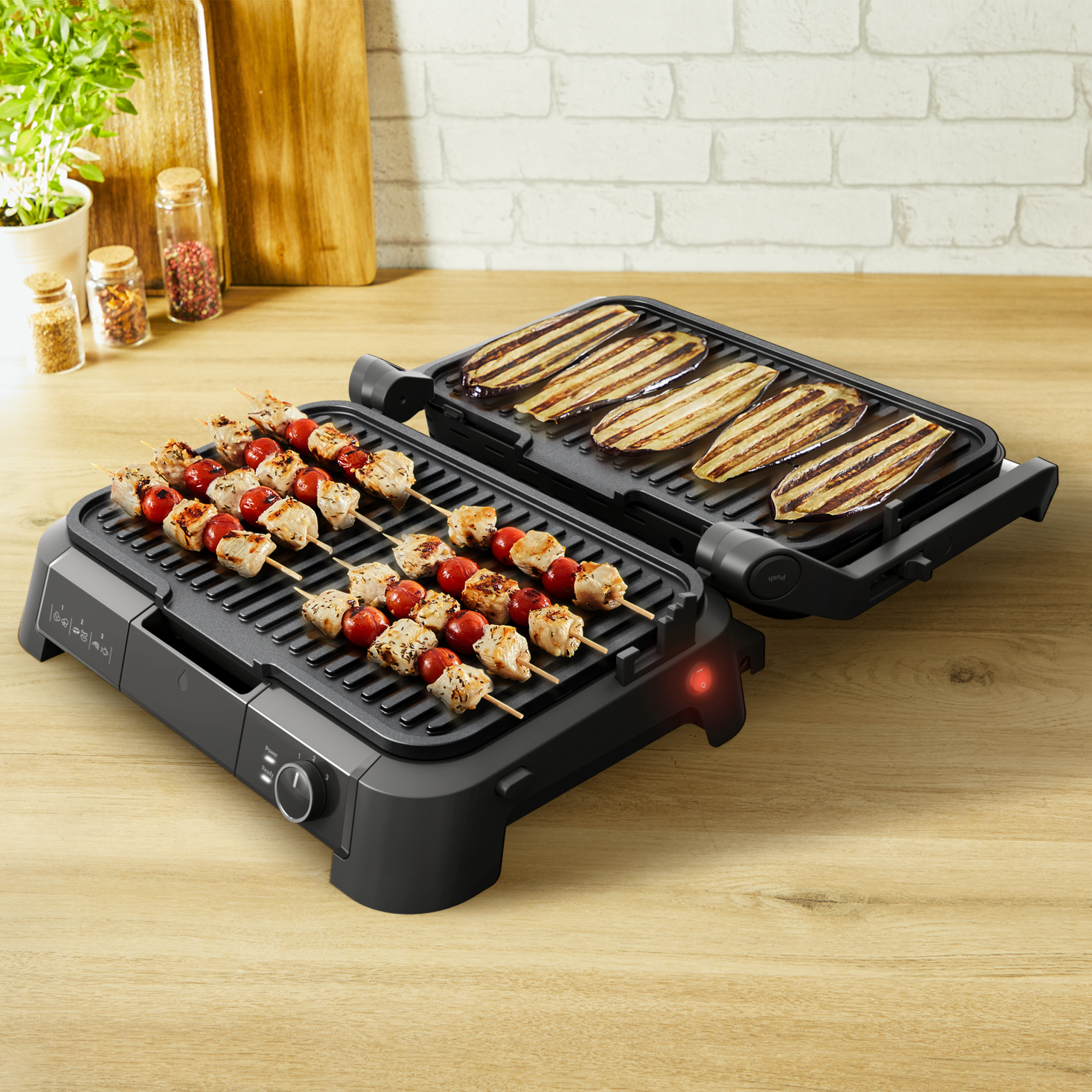 Offener Elektrogrill mit Essen. Spieße mit Hähnchen und Tomaten, sowie gegrillte Aubergine.