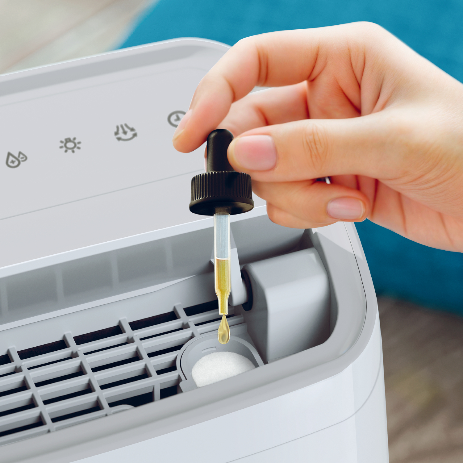 Dłoń dodająca krople płynu z zakraplacza do białej maszyny.