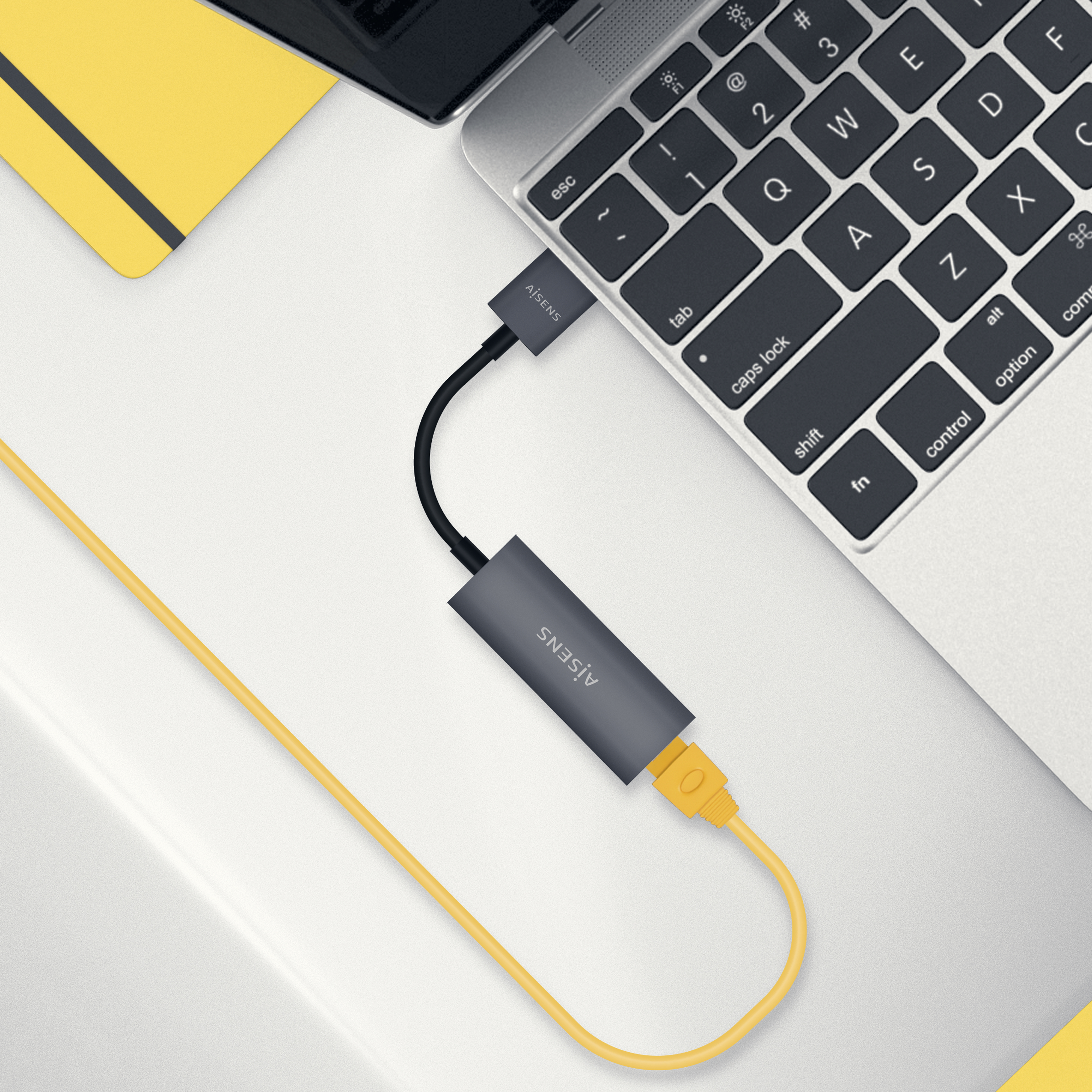 Laptop, der über ein gelbes Kabel mit einem USB-zu-Ethernet-Adapter verbunden ist.