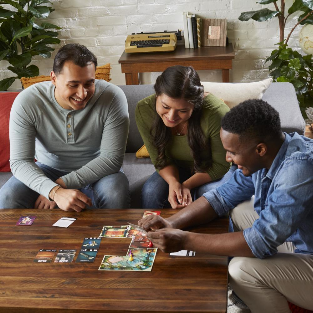 Drie mensen die een bordspel spelen aan een tafel.