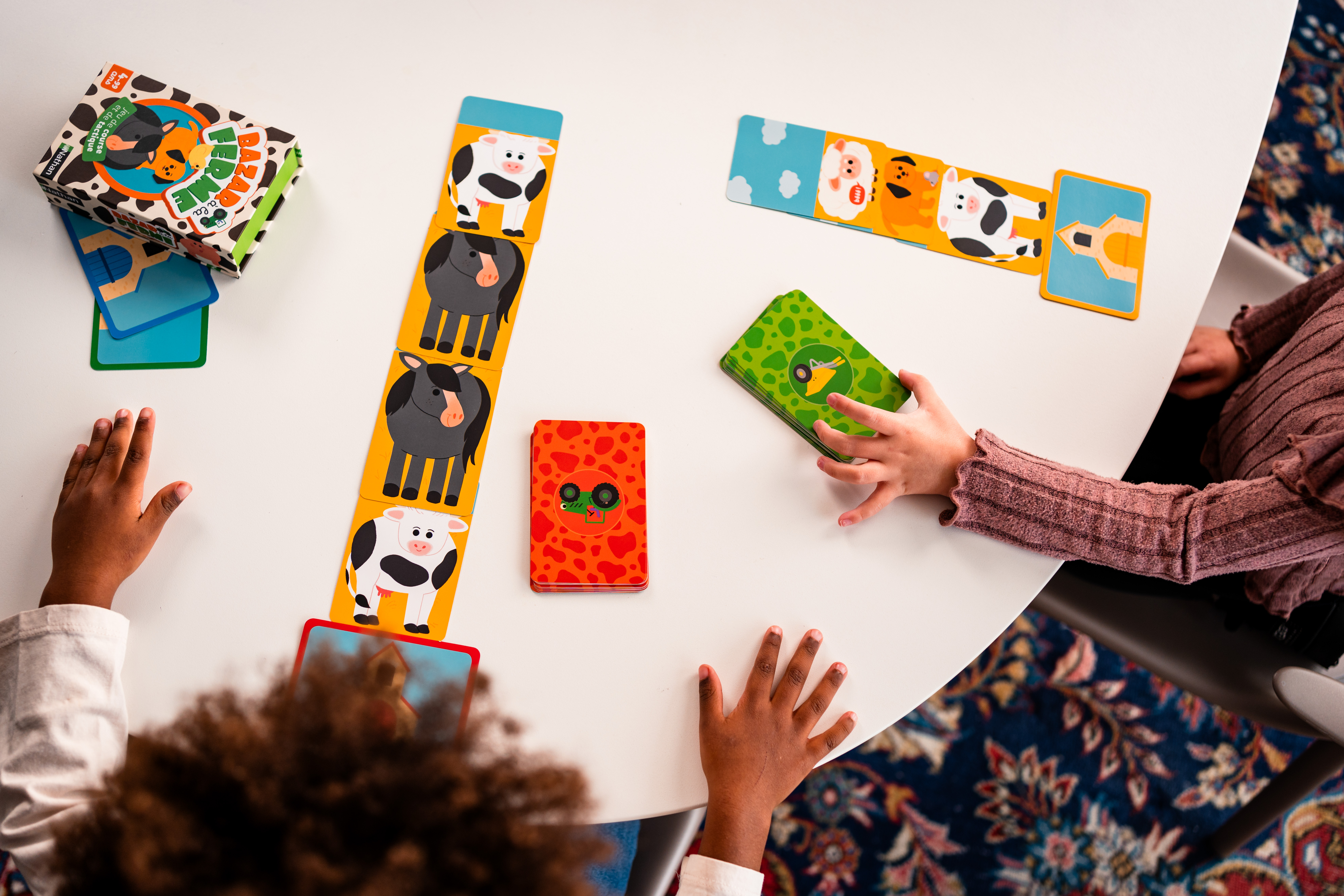 Dzieci grają w grę dopasowywania. Karty z obrazami krów są na stole, a ręce sięgają po nie.