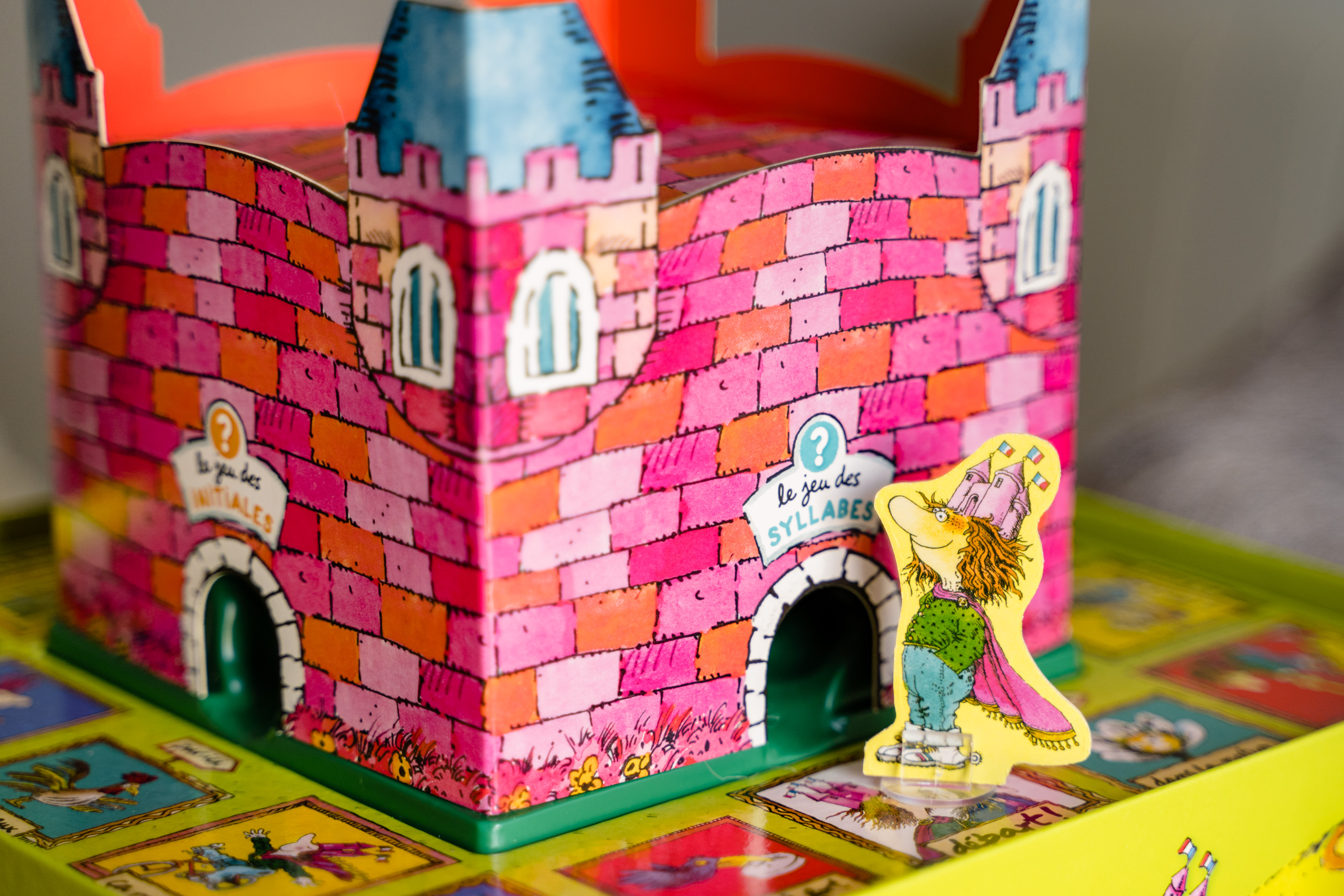 Un gioco da tavolo con un castello rosa e una figura dei cartoni animati. Il gioco è su un tabellone.