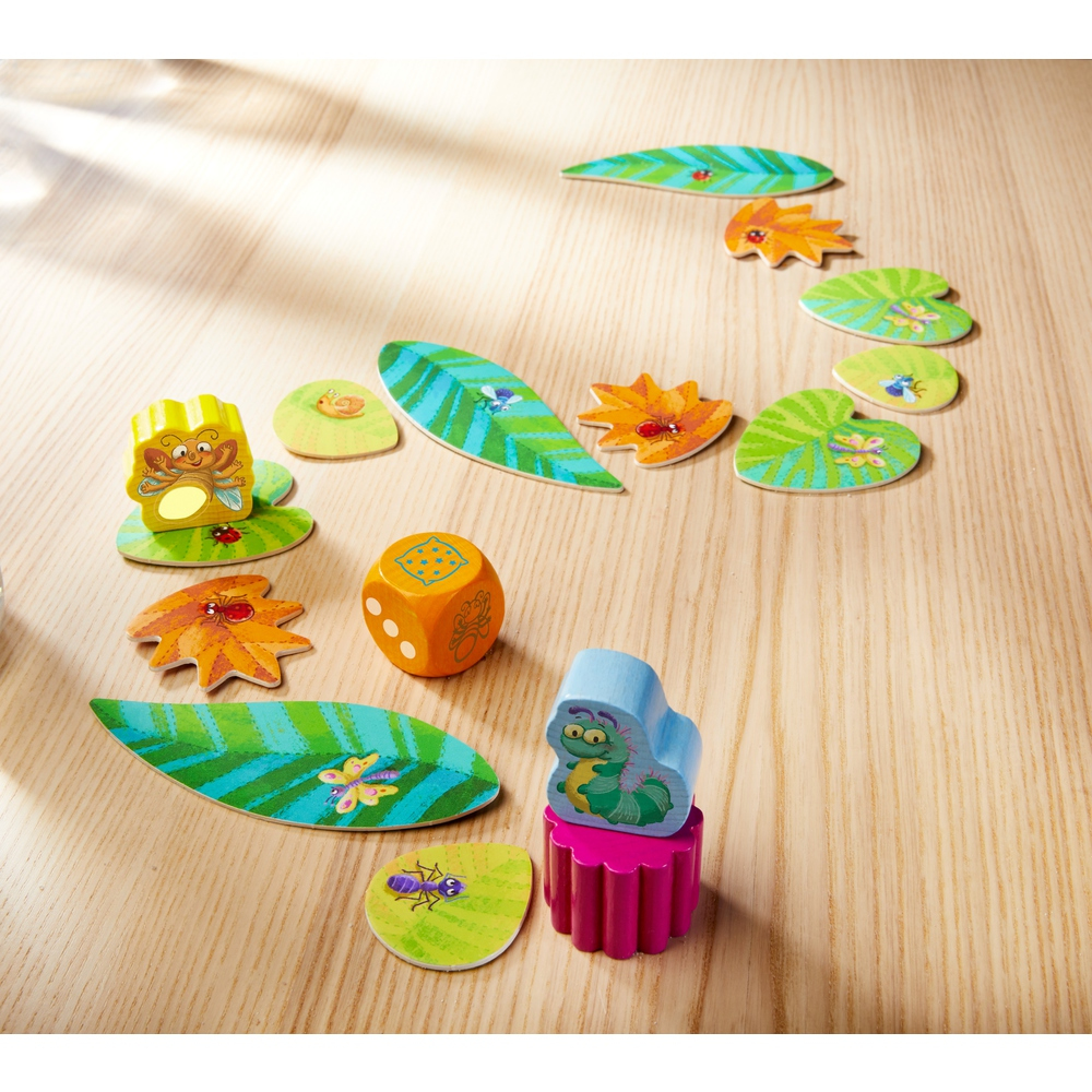 Holzspiel mit Blättern, Würfeln und Käfern auf Holzoberfläche.