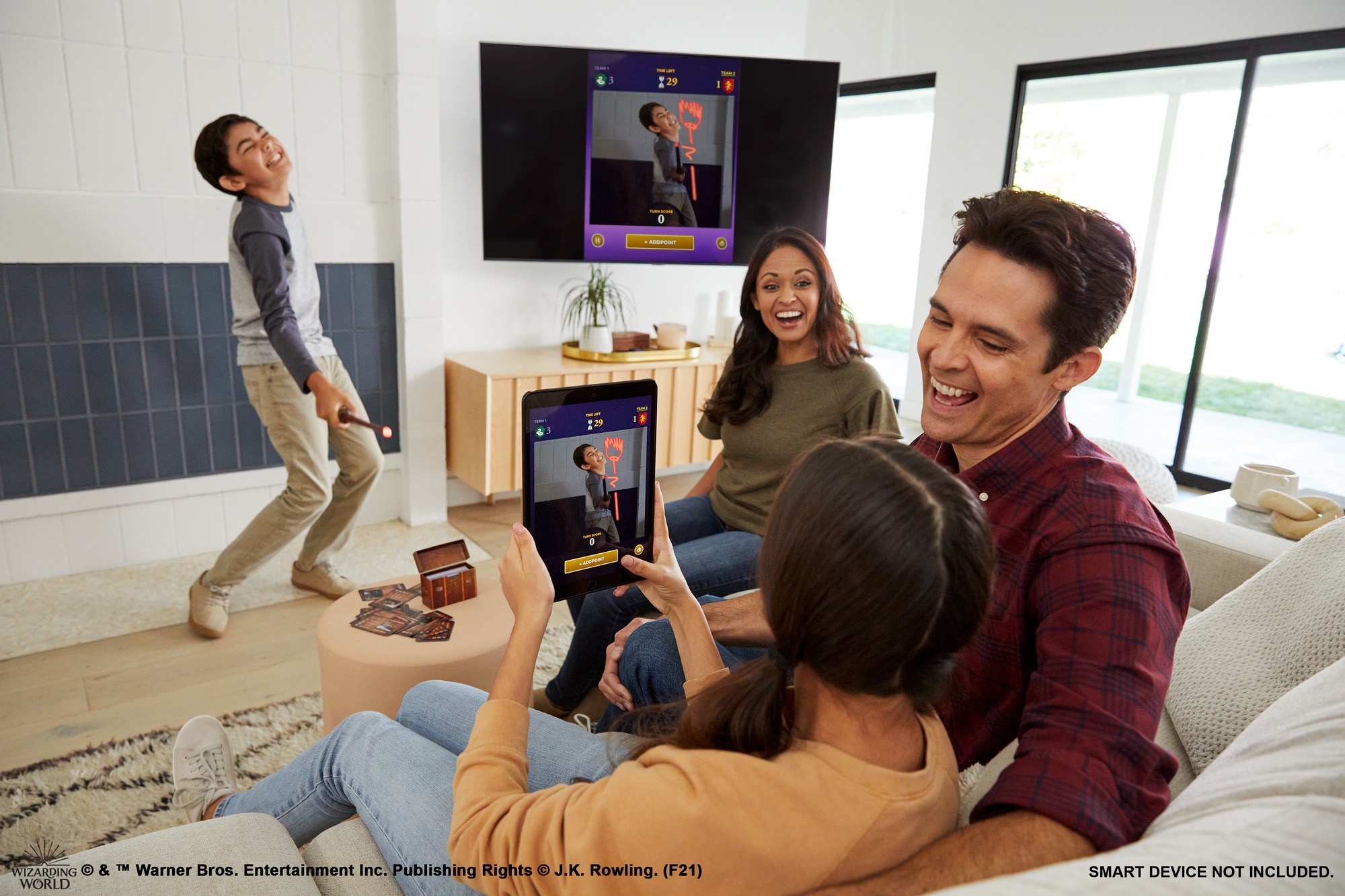 Rodzina gra w salonie. Chłopiec jest podekscytowany, trzymając różdżkę.