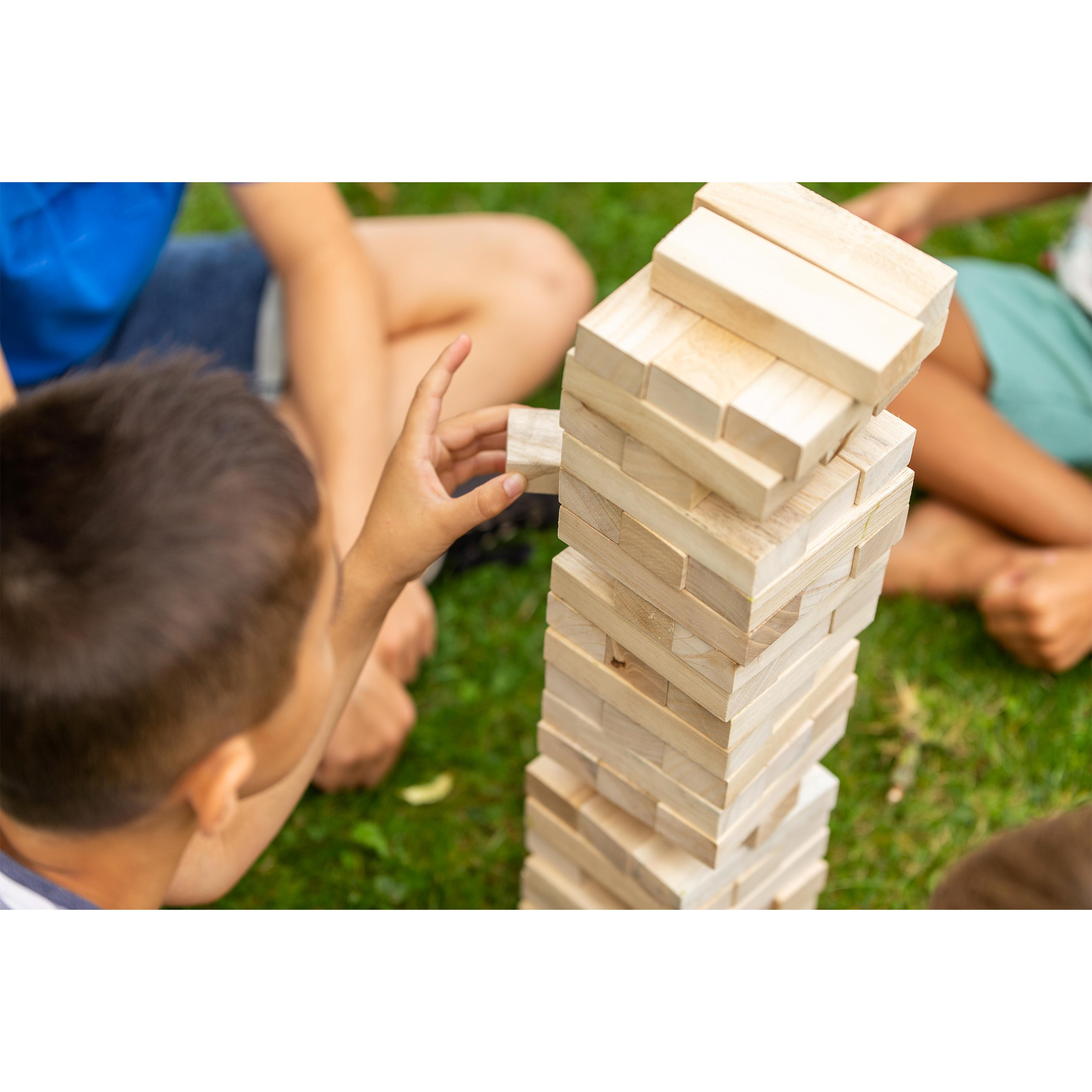 Primo piano della mano di un bambino che rimuove un blocco da una torre Jenga.