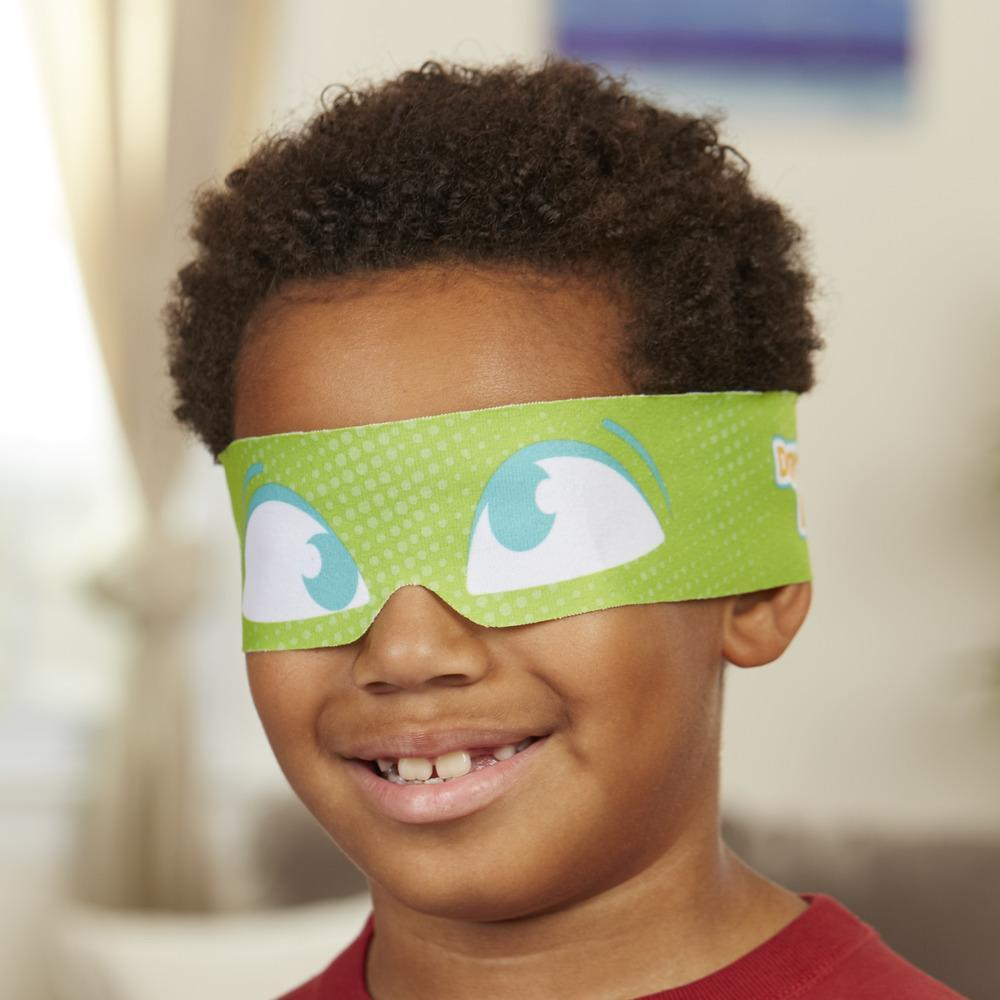 Mały chłopiec w zielonej opasce z nadrukowanymi oczami. Uśmiecha się.
