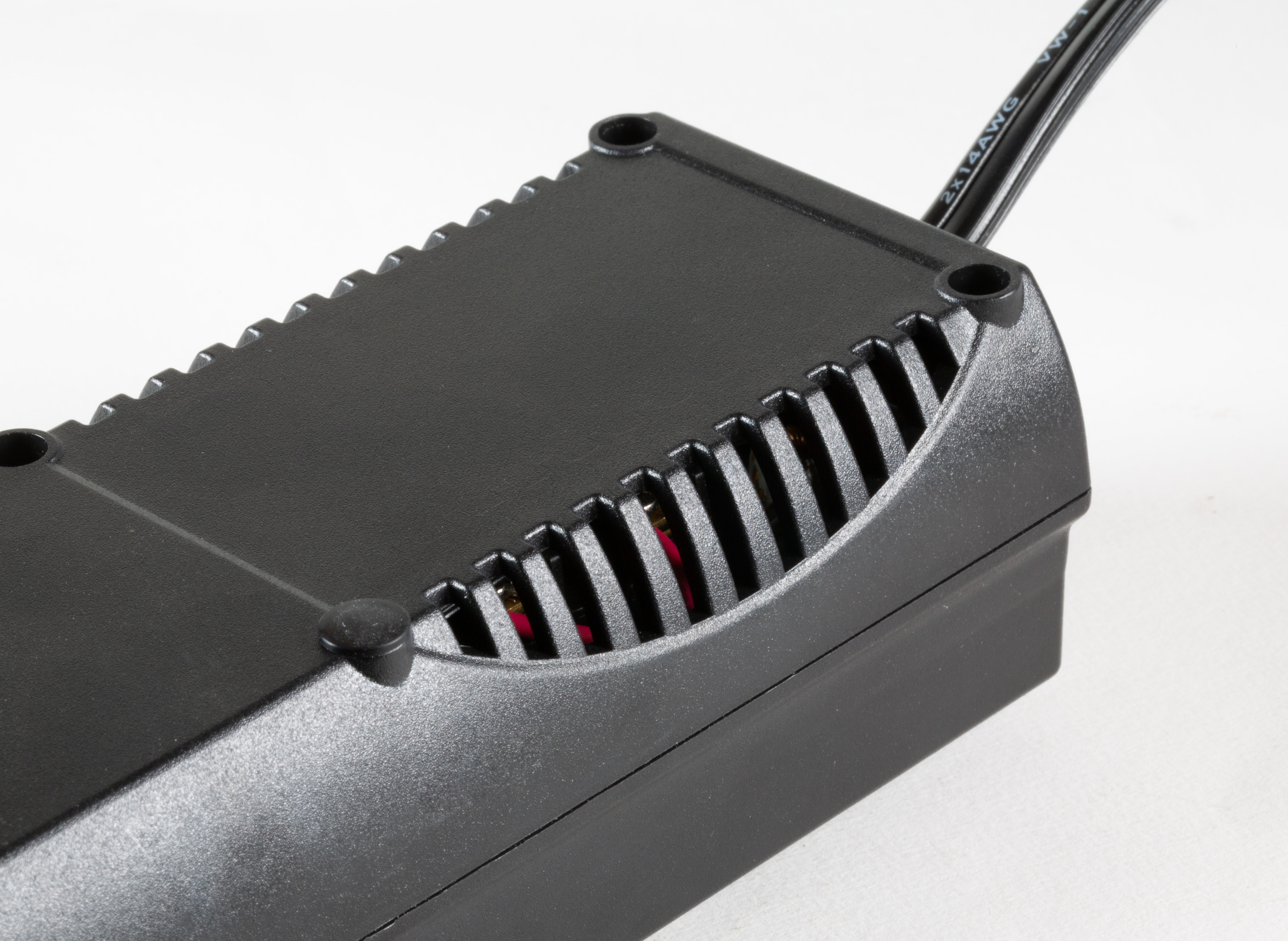 Czarny, żebrowany zasilacz z otworami wentylacyjnymi z boku, widok z góry.